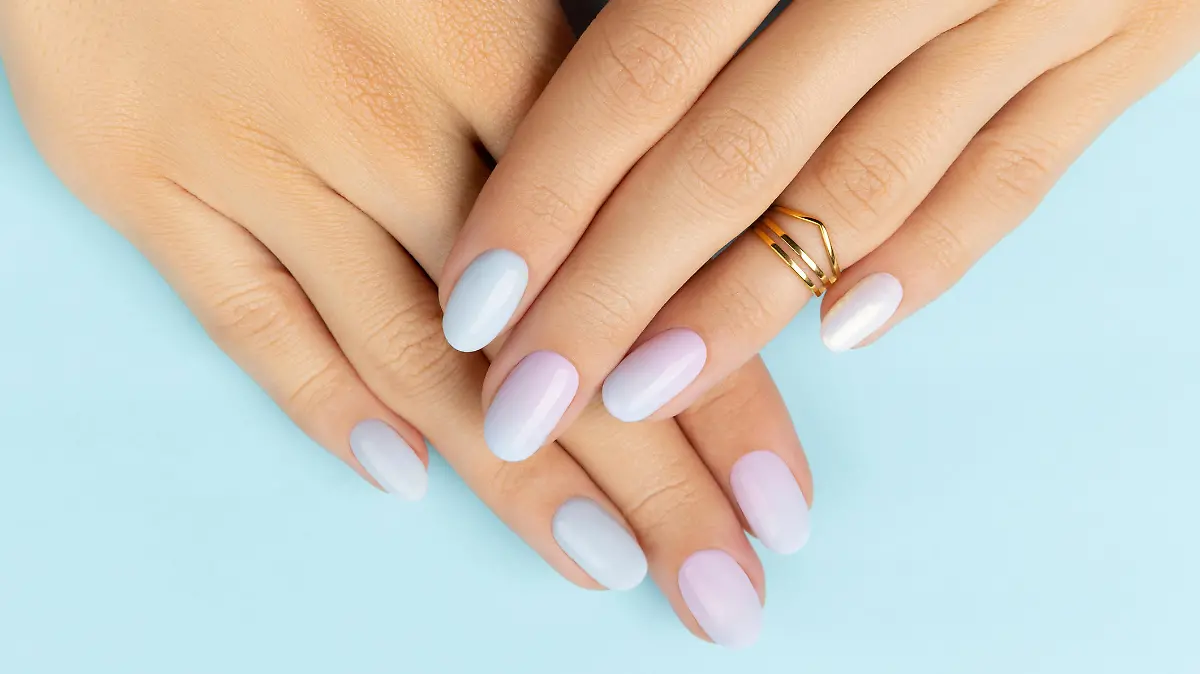 Womans hands with trendy manicure on blue background. Summer nail design. Beauty salon concept