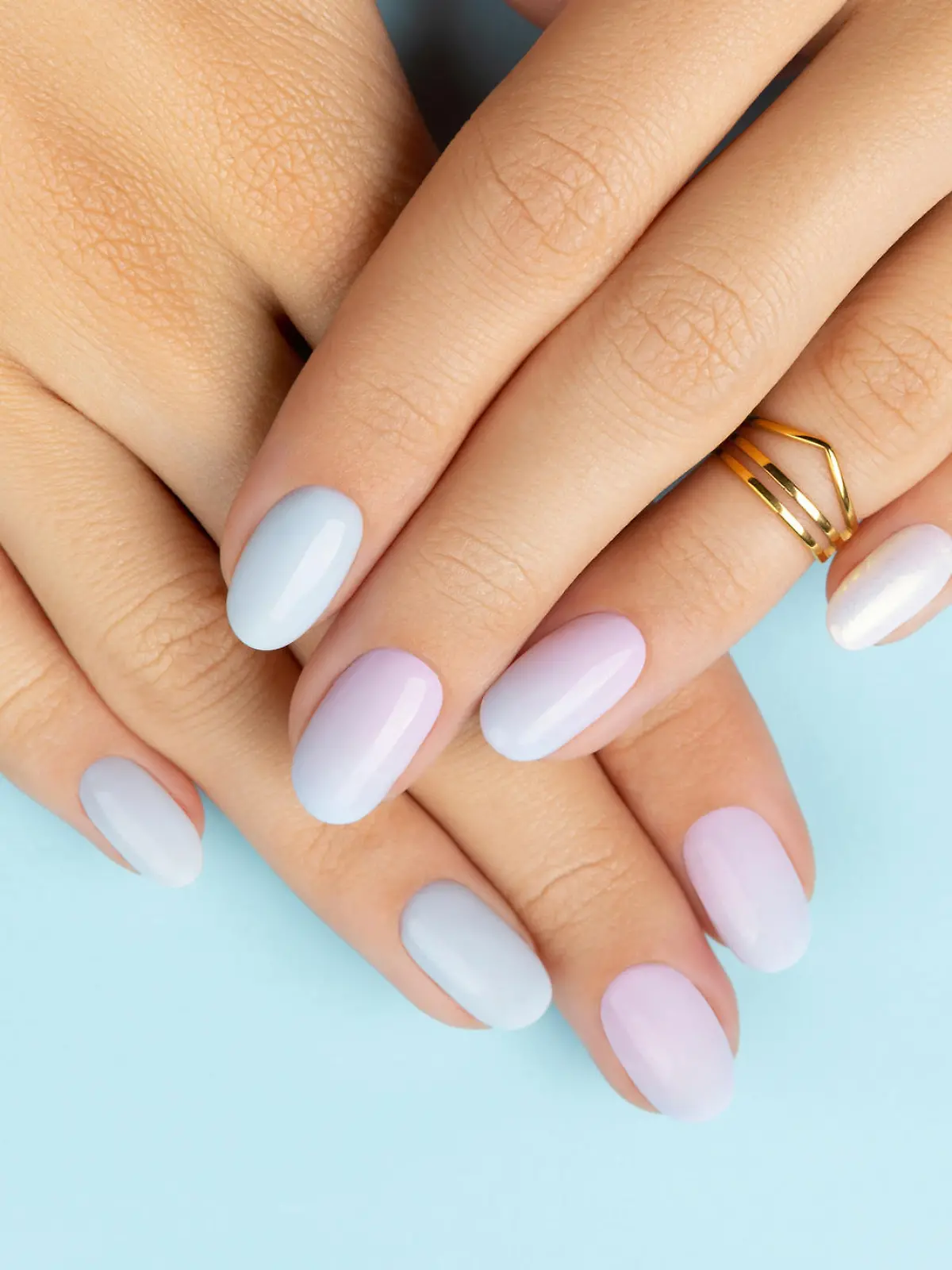 Womans hands with trendy manicure on blue background. Summer nail design. Beauty salon concept