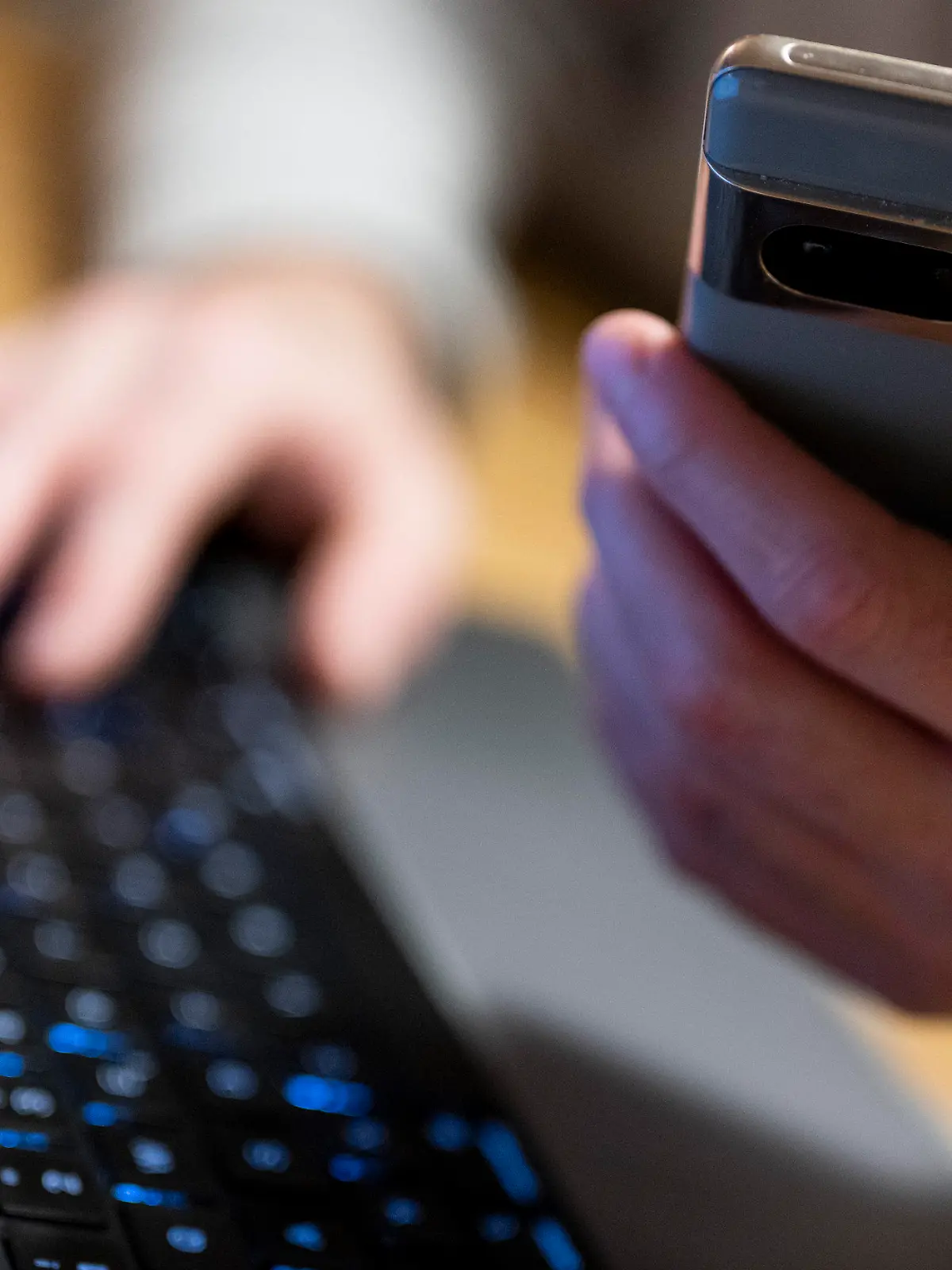 ILLUSTRATION - 27.02.2023, Berlin: Ein Mann sitzt am Laptop und hält ein Smartphone mit in der Hand. (zu dpa: «Mann will Geld investieren und wird um 75 000 Euro betrogen») Foto: Monika Skolimowska/dpa +++ dpa-Bildfunk +++
