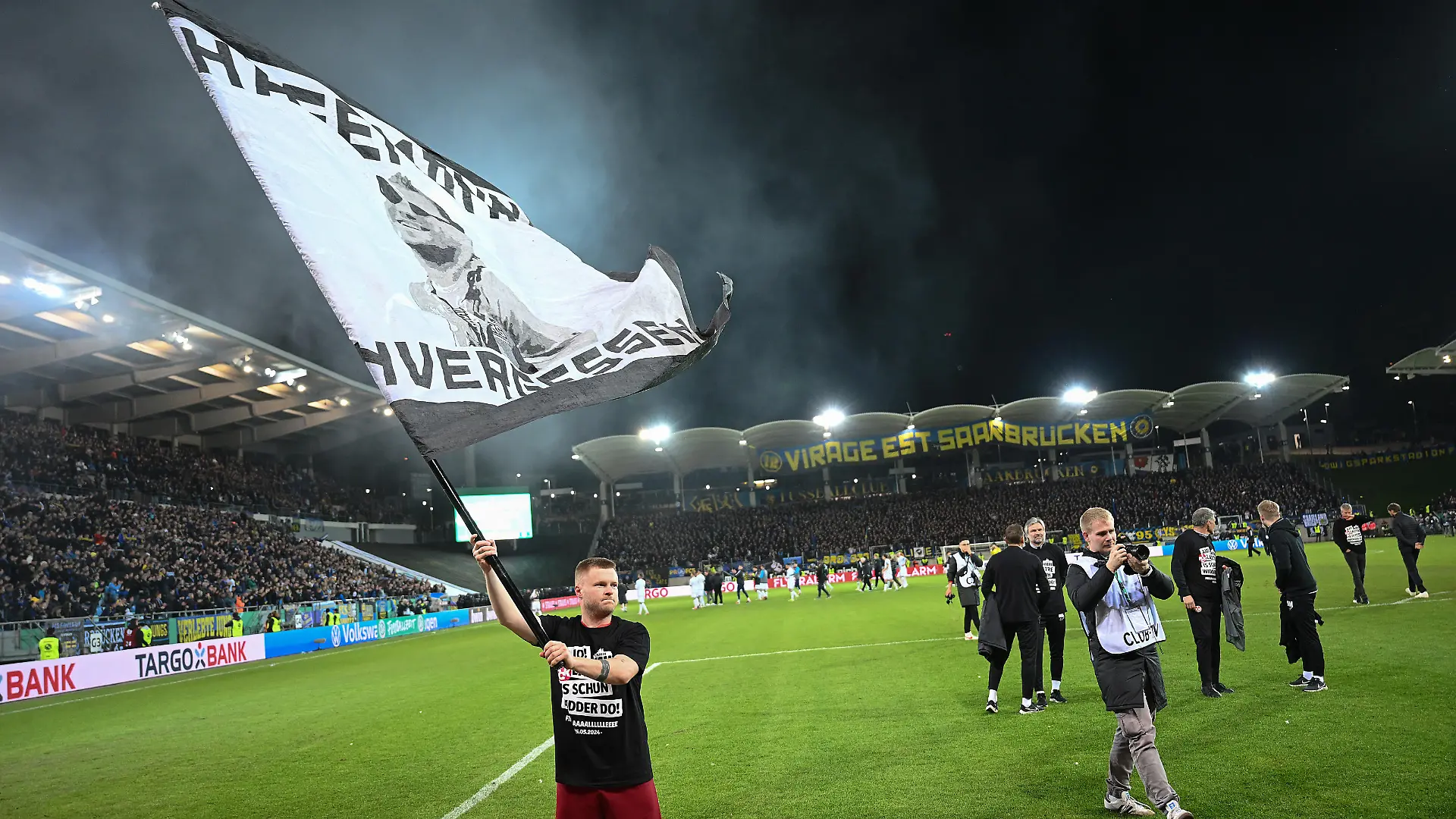 SAARBRUECKEN, GERMANY - APRIL 02: Jean Zimmer of 1. FC Kaiserslautern celebrates after the team's victory with a flag during the DFB Cup semifinal match between 1. FC Saarbrücken and 1. FC Kaiserslautern at the Ludwigsparkstadion on April 02, 2024 in Saarbruecken, Germany. (Photo by Christian Kaspar-Bartke/Getty Images)