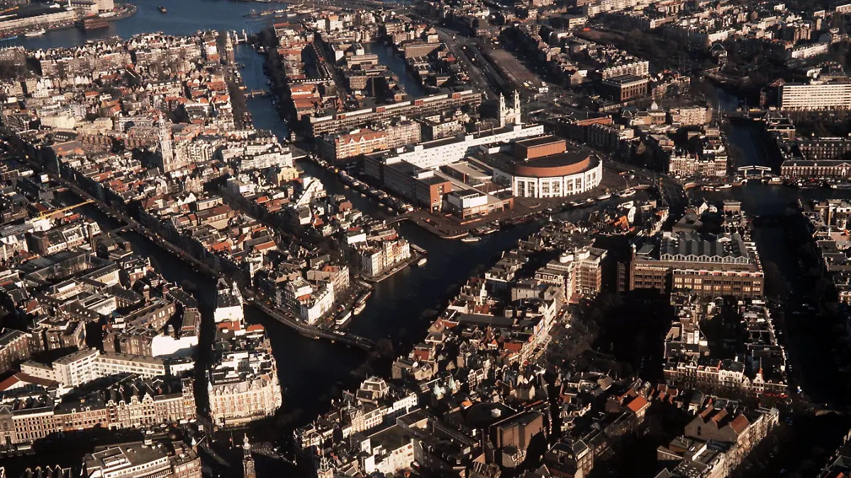 Blick aus der Luft auf die niederländische Stadt Amsterdam mit ihren Grachten. In der Mitte hinten der halbrunde Bau des Musiktheaters.(Aufnahme von 1990)