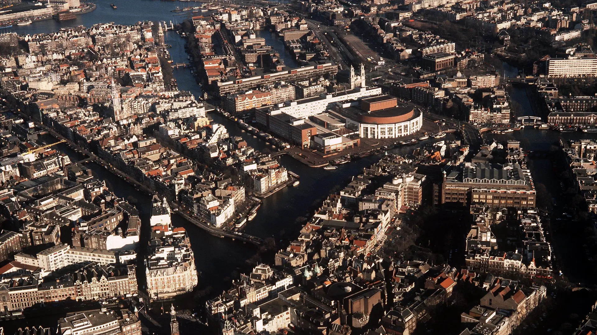 Blick aus der Luft auf die niederländische Stadt Amsterdam mit ihren Grachten. In der Mitte hinten der halbrunde Bau des Musiktheaters.(Aufnahme von 1990)
