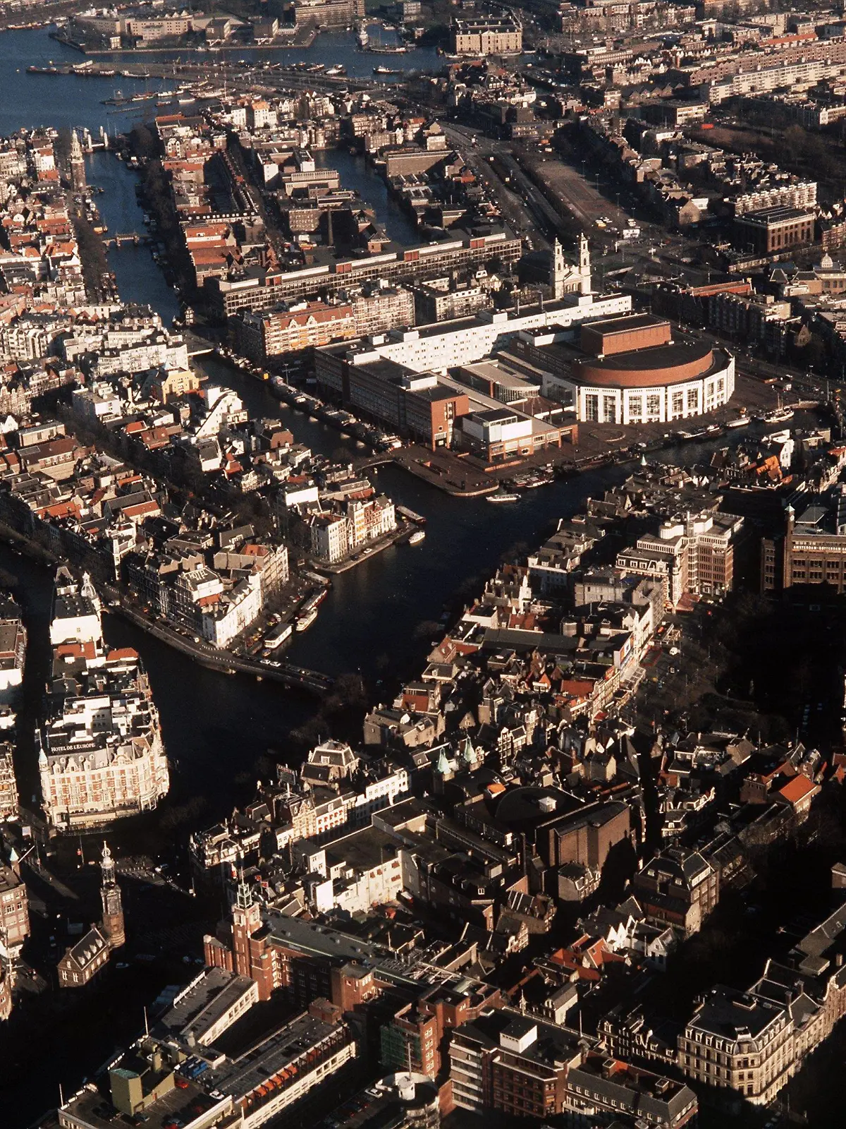 Blick aus der Luft auf die niederländische Stadt Amsterdam mit ihren Grachten. In der Mitte hinten der halbrunde Bau des Musiktheaters.(Aufnahme von 1990)