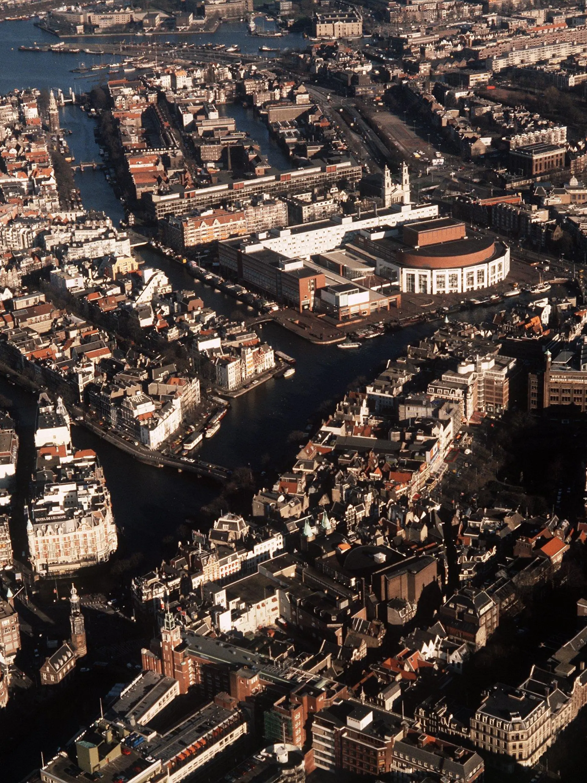 Blick aus der Luft auf die niederländische Stadt Amsterdam mit ihren Grachten. In der Mitte hinten der halbrunde Bau des Musiktheaters.(Aufnahme von 1990)