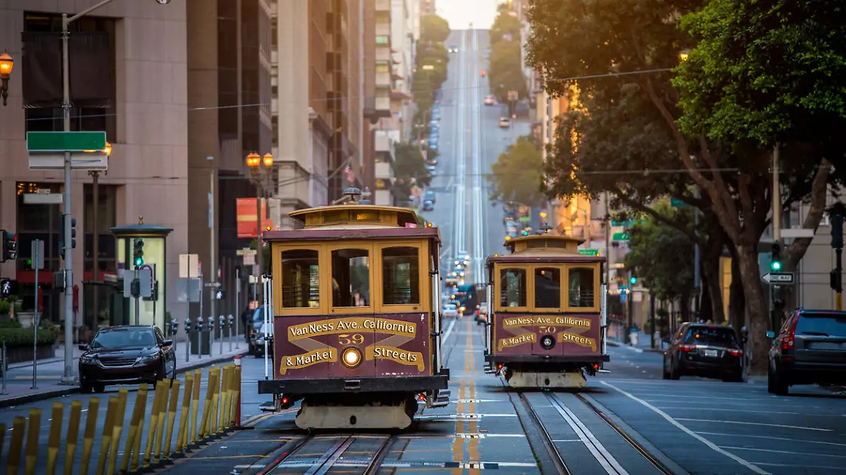Classic view of historic traditional Cable Cars riding on famous California Street in beautiful early morning light at sunrise in summer, San Francisco, California, USA
