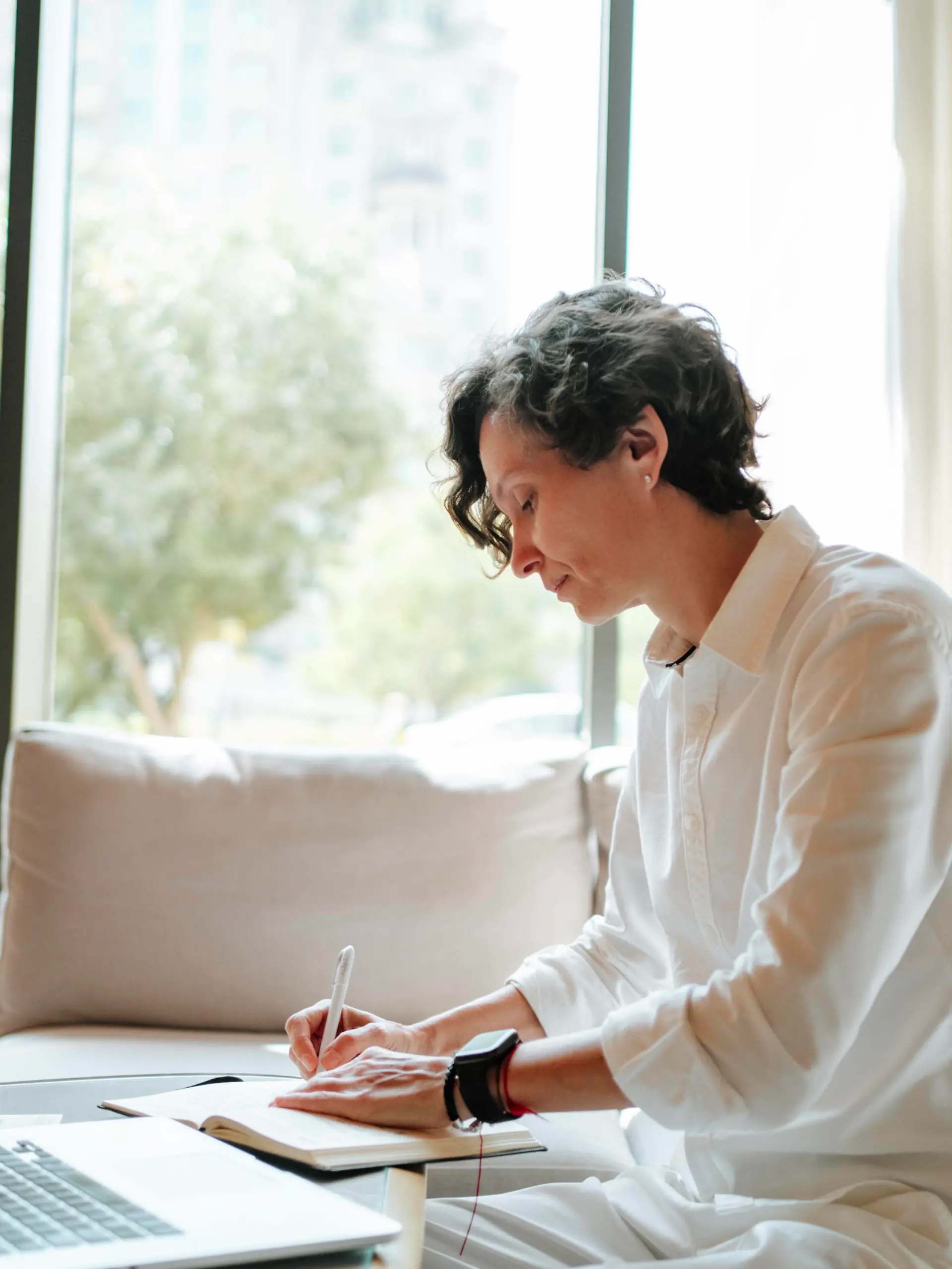Confident businesswoman writing in diary by laptop at hotel lobby model released, Symbolfoto property released, MDOF01880