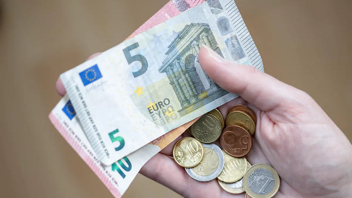 ACHTUNG: SPERRFRIST 6. JANUAR 05:00 UHR. - ARCHIV - 09.04.2021, Bayern, Nürnberg: Eine Frau hält Geldscheine und Münzen in der Hand. Fast ein Fünftel aller Vollzeitbeschäftigten in Deutschland sind Geringverdiener. Sie müssen mit einem Bruttoarbeitsentgelt unter 2284 Euro im Monat über die Runden kommen. Das geht aus einer Studie des Wirtschafts- und Sozialwissenschaftlichen Instituts (WSI) der gewerkschaftsnahen Hans-Böckler-Stiftung hervor. (zu dpa "Fast jeder dritte Vollzeitbeschäftigte in Brandenburg Geringverdiener") Foto: Daniel Karmann/dpa +++ dpa-Bildfunk +++