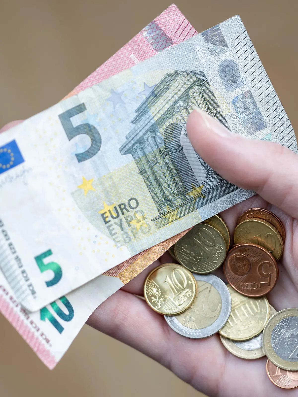 ACHTUNG: SPERRFRIST 6. JANUAR 05:00 UHR.  - ARCHIV - 09.04.2021, Bayern, Nürnberg: Eine Frau hält Geldscheine und Münzen in der Hand. Fast ein Fünftel aller Vollzeitbeschäftigten in Deutschland sind Geringverdiener. Sie müssen mit einem Bruttoarbeitsentgelt unter 2284 Euro im Monat über die Runden kommen. Das geht aus einer Studie des Wirtschafts- und Sozialwissenschaftlichen Instituts (WSI) der gewerkschaftsnahen Hans-Böckler-Stiftung hervor. (zu dpa "Fast jeder dritte Vollzeitbeschäftigte in Brandenburg Geringverdiener") Foto: Daniel Karmann/dpa +++ dpa-Bildfunk +++
