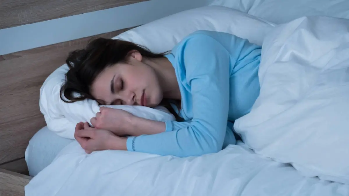 schlafende junge frau auf dem bett in ihrem schlafzimmer