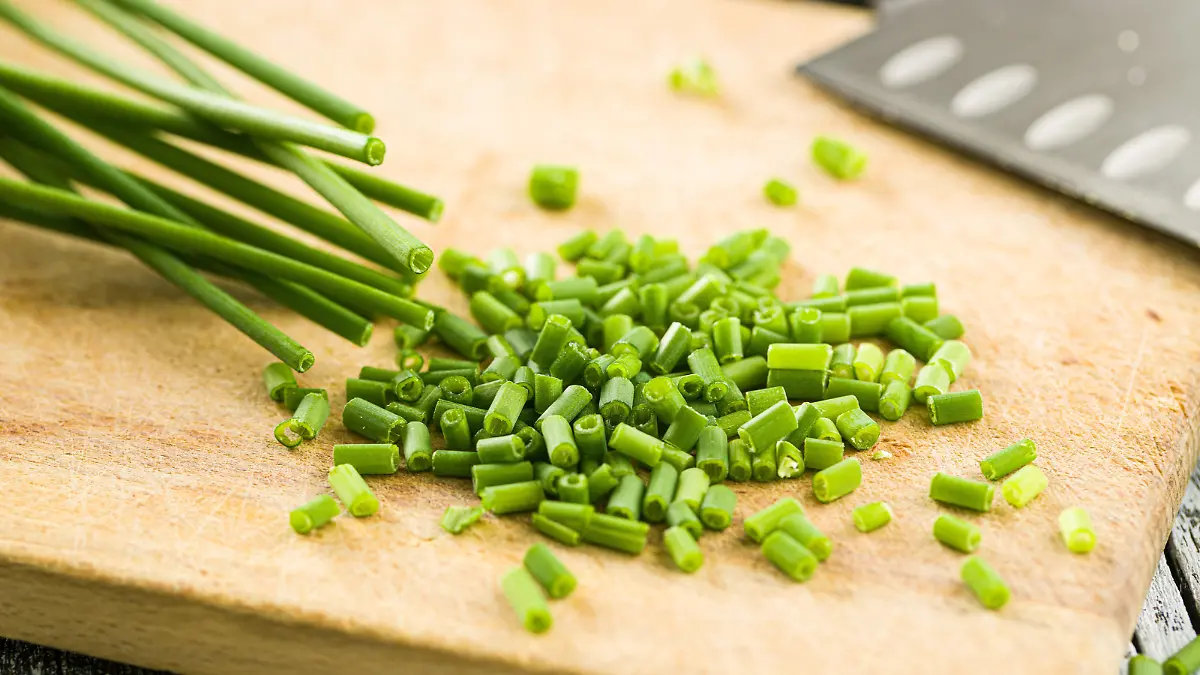 Chopped green chives on old wooden table.
