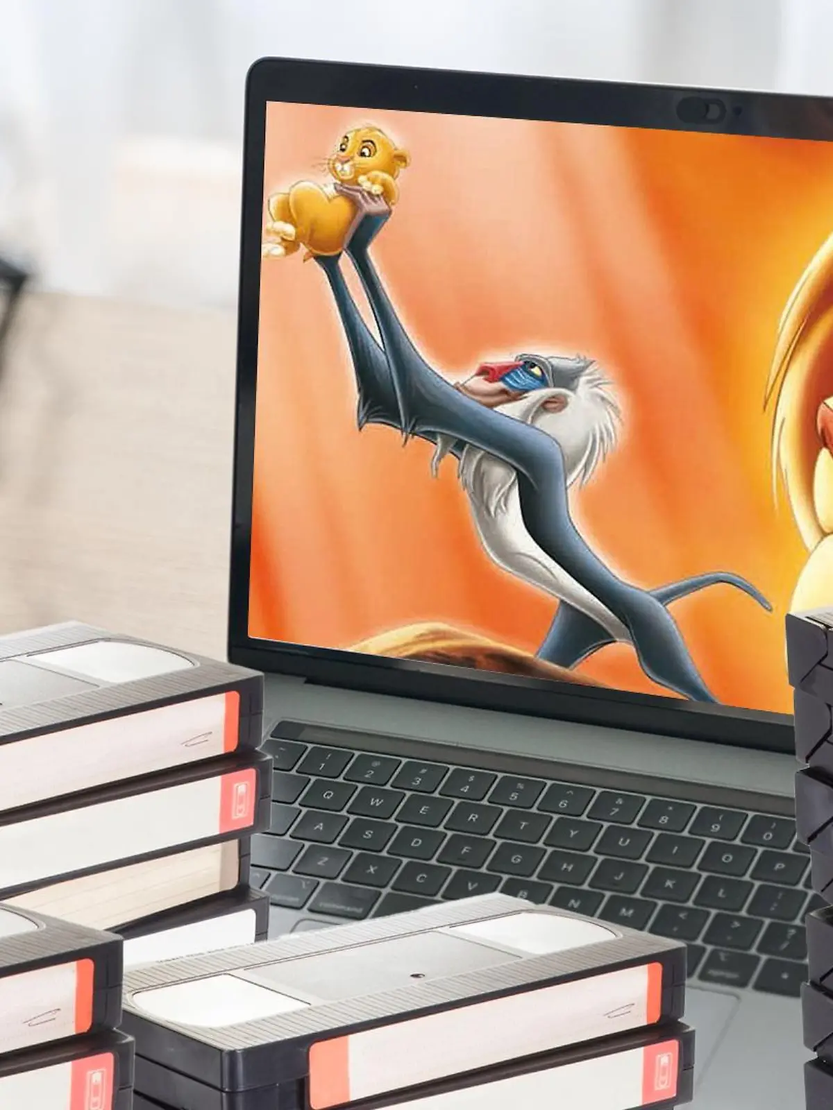 Eine Frau schaut König der Löwen an ihrem Pc und um sie herum sind mehrere VHS-Kassetten.