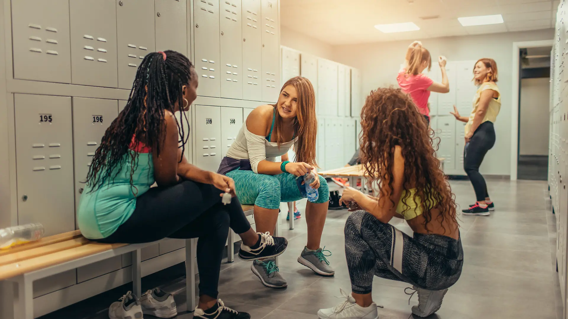 Group of women talking in locker room before dancing class.