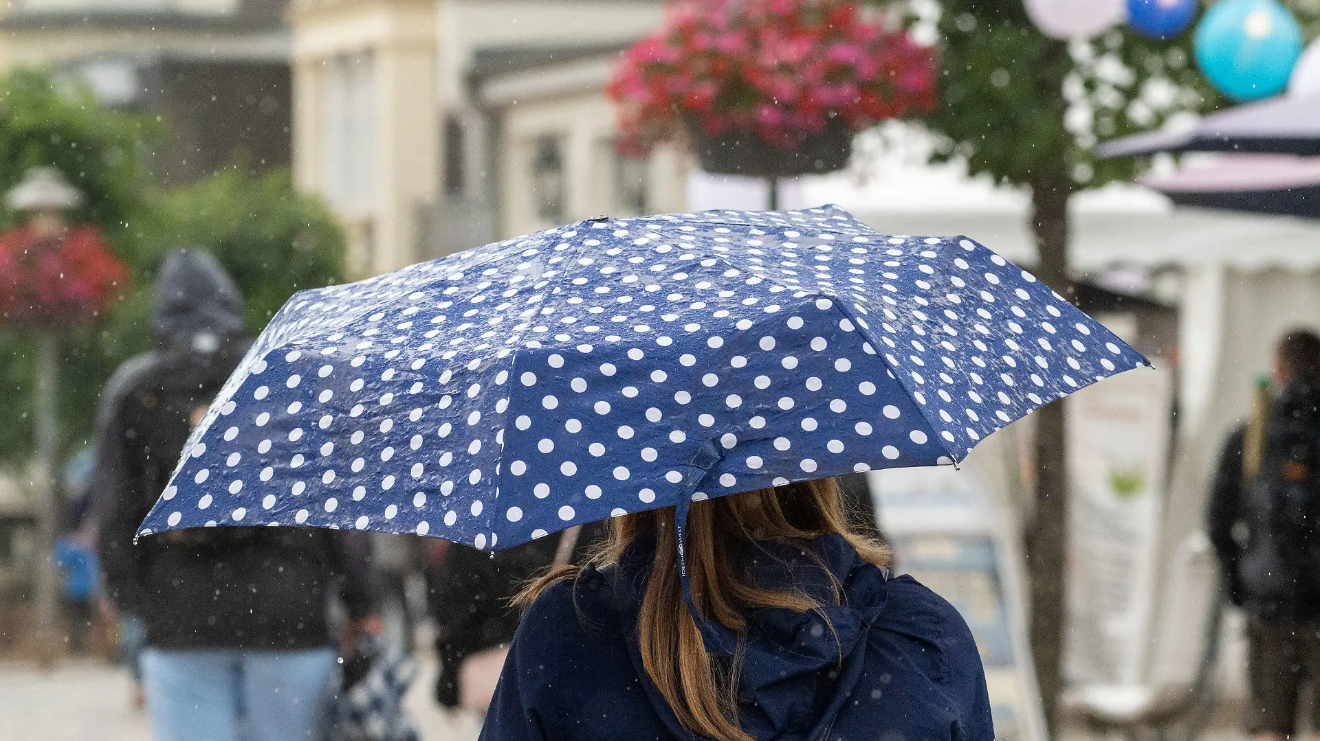 22.07.2023, Mecklenburg-Vorpommern, Zinnowitz: Touristen laufen im Regen auf der Strandpromenade des Seebades Zinnowitz auf der Insel Usedom. Die Meteorologen erwarten auch in den kommenden Tagen wechselhaftes Wetter an der Ostsee. Das Wetter meint es derzeit nicht gut mit dem Urlaubsland Mecklenburg-Vorpommern. Da der Trend zum kurzfristigen Buchen gehe, habe das Wetter einen Einfluss auf die Entscheidung, wohin in den Urlaub gefahren werde, sagte der Geschäftsführer des Landestourismusverbandes. Foto: Stefan Sauer/dpa +++ dpa-Bildfunk +++