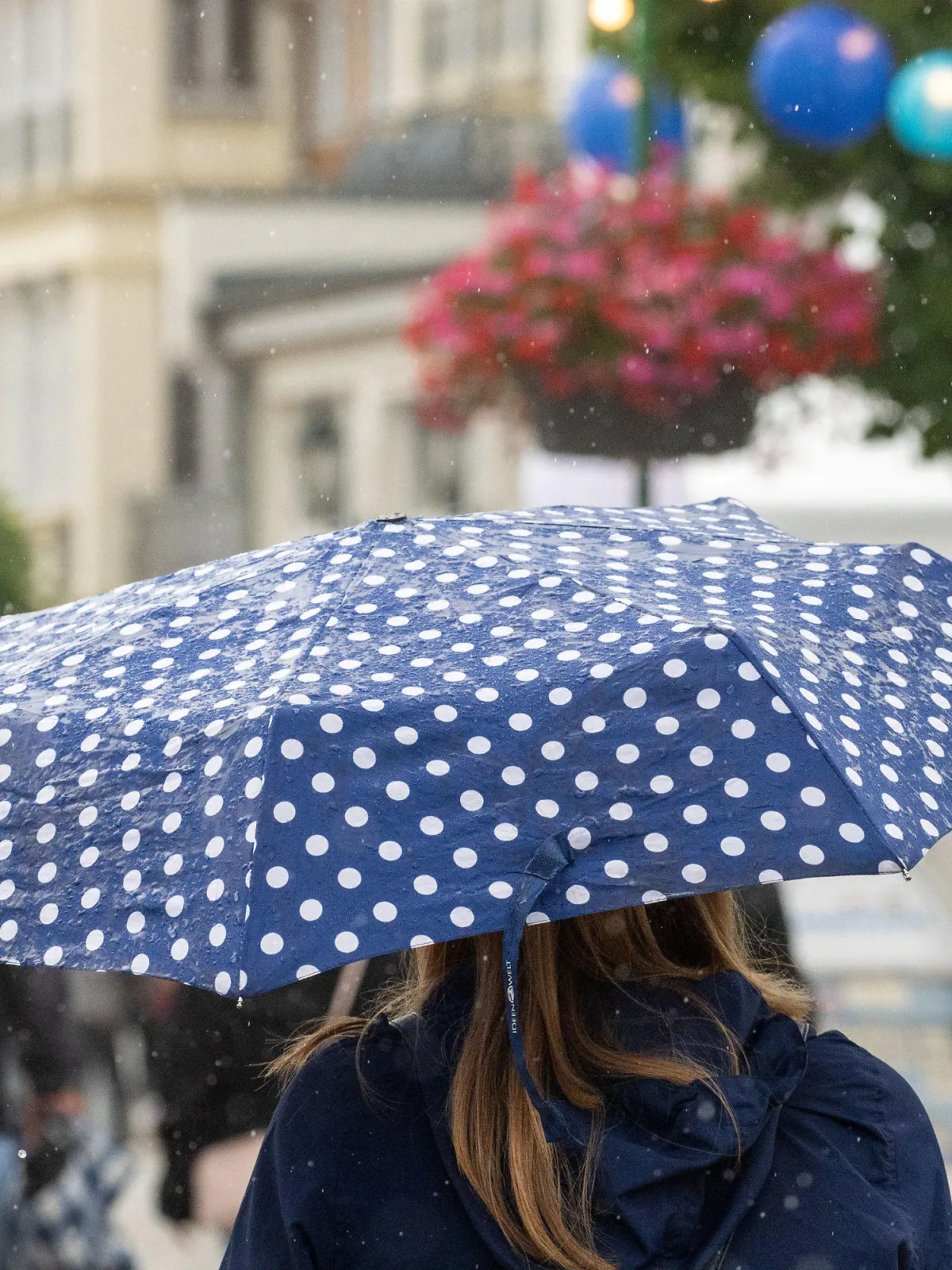 22.07.2023, Mecklenburg-Vorpommern, Zinnowitz: Touristen laufen im Regen auf der Strandpromenade des Seebades Zinnowitz auf der Insel Usedom. Die Meteorologen erwarten auch in den kommenden Tagen wechselhaftes Wetter an der Ostsee. Das Wetter meint es derzeit nicht gut mit dem Urlaubsland Mecklenburg-Vorpommern. Da der Trend zum kurzfristigen Buchen gehe, habe das Wetter einen Einfluss auf die Entscheidung, wohin in den Urlaub gefahren werde, sagte der Geschäftsführer des Landestourismusverbandes. Foto: Stefan Sauer/dpa +++ dpa-Bildfunk +++