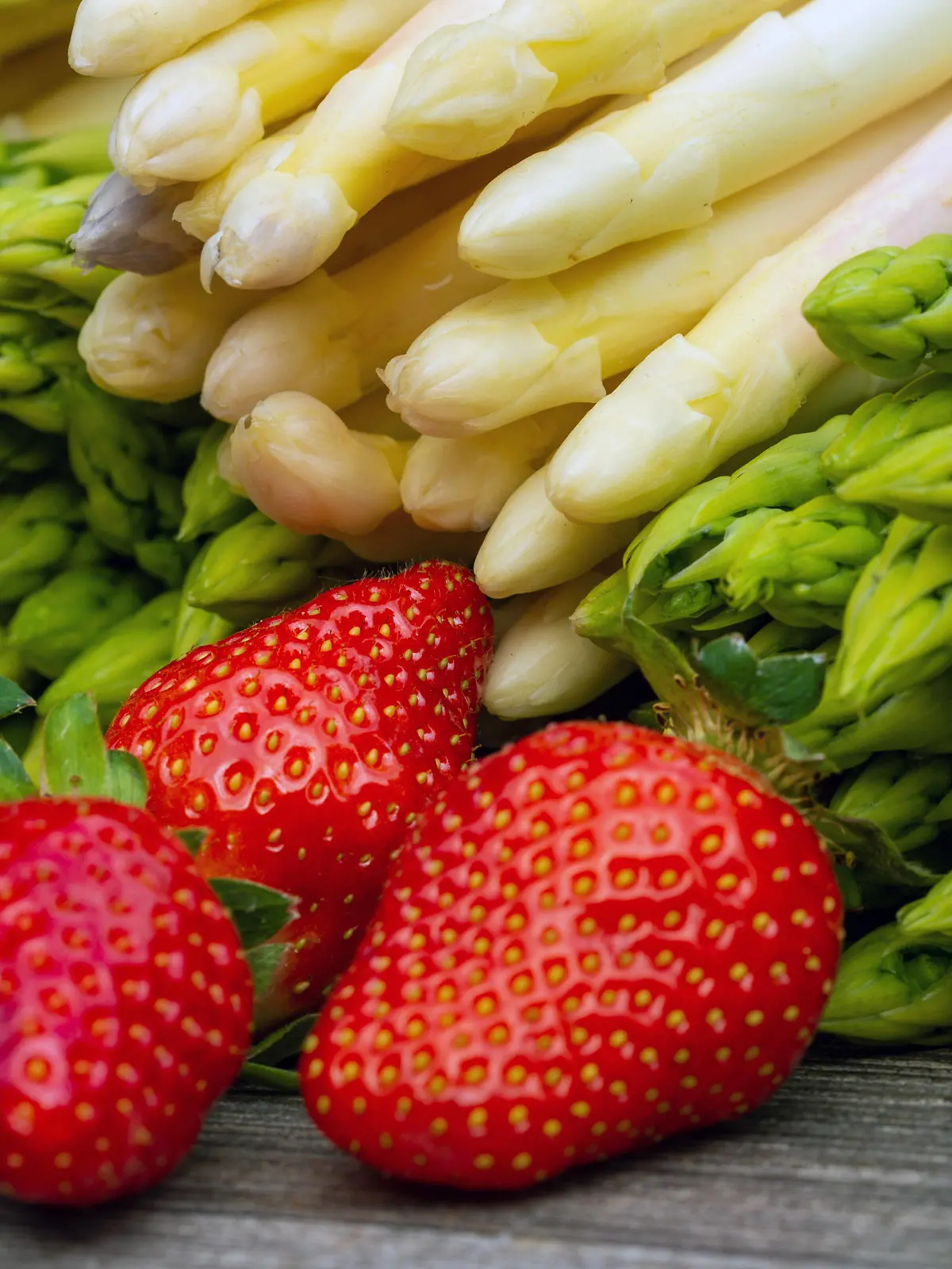 Grüne Spargel, weiße Spargel und frische Erdbeeren dekoriert auf einem rustikalen Holztisch *** Green asparagus, white asparagus and fresh strawberries decorated on a rustic wooden table Copyright: xx