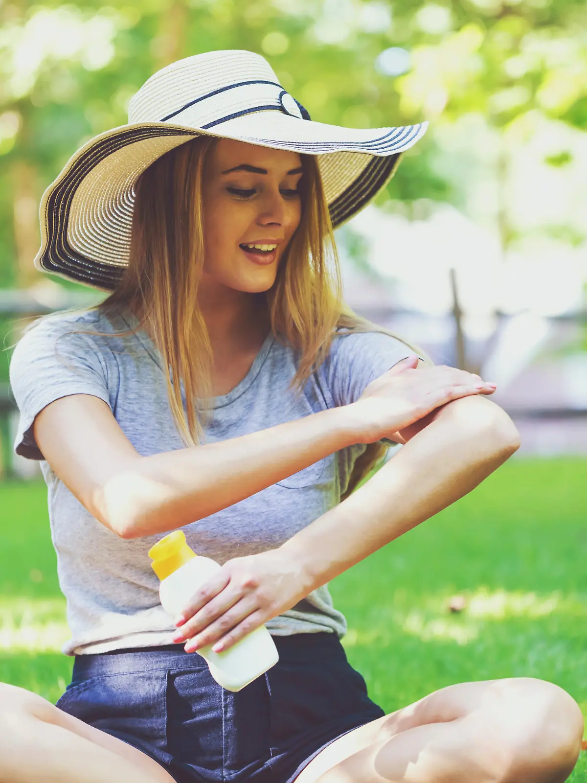 Young woman a bottle of sunblock outside on a summer day