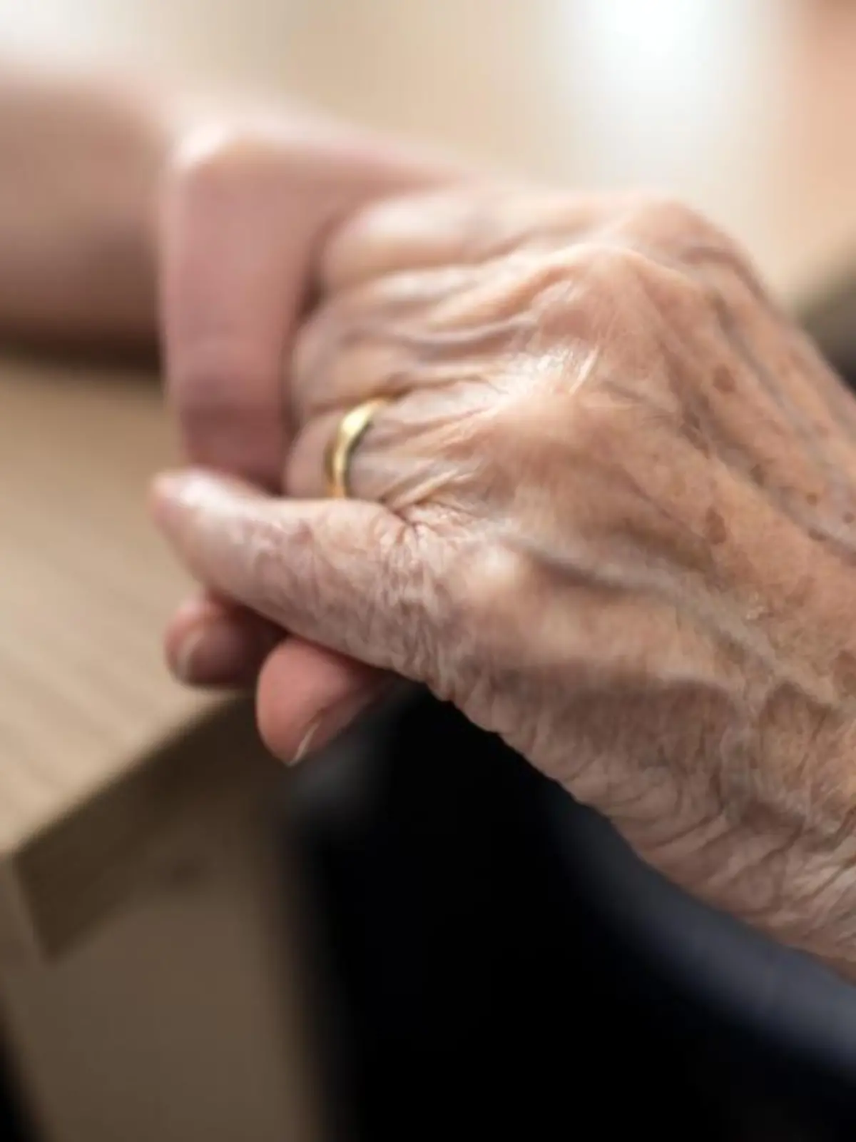 Eine Pflegerin hält die Hand einer alten Frau in einem Altenheim
