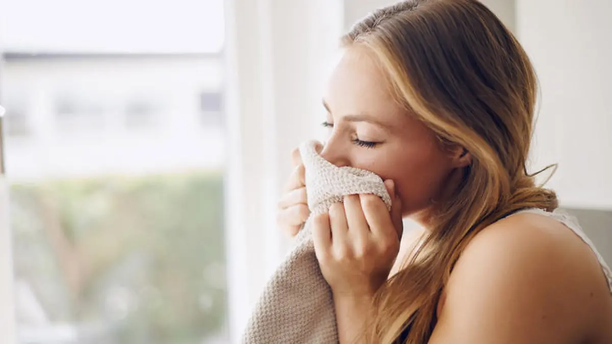 Shot of a young woman smelling fresh laundry at home