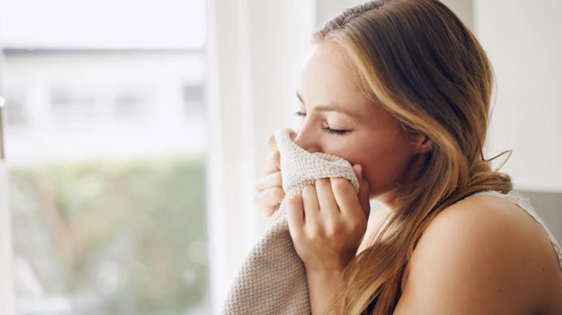 Shot of a young woman smelling fresh laundry at home