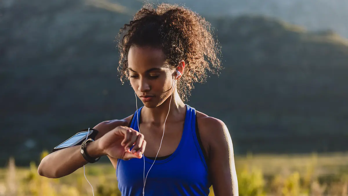 Cropped shot of a woman checking her wristwatch while out for a run