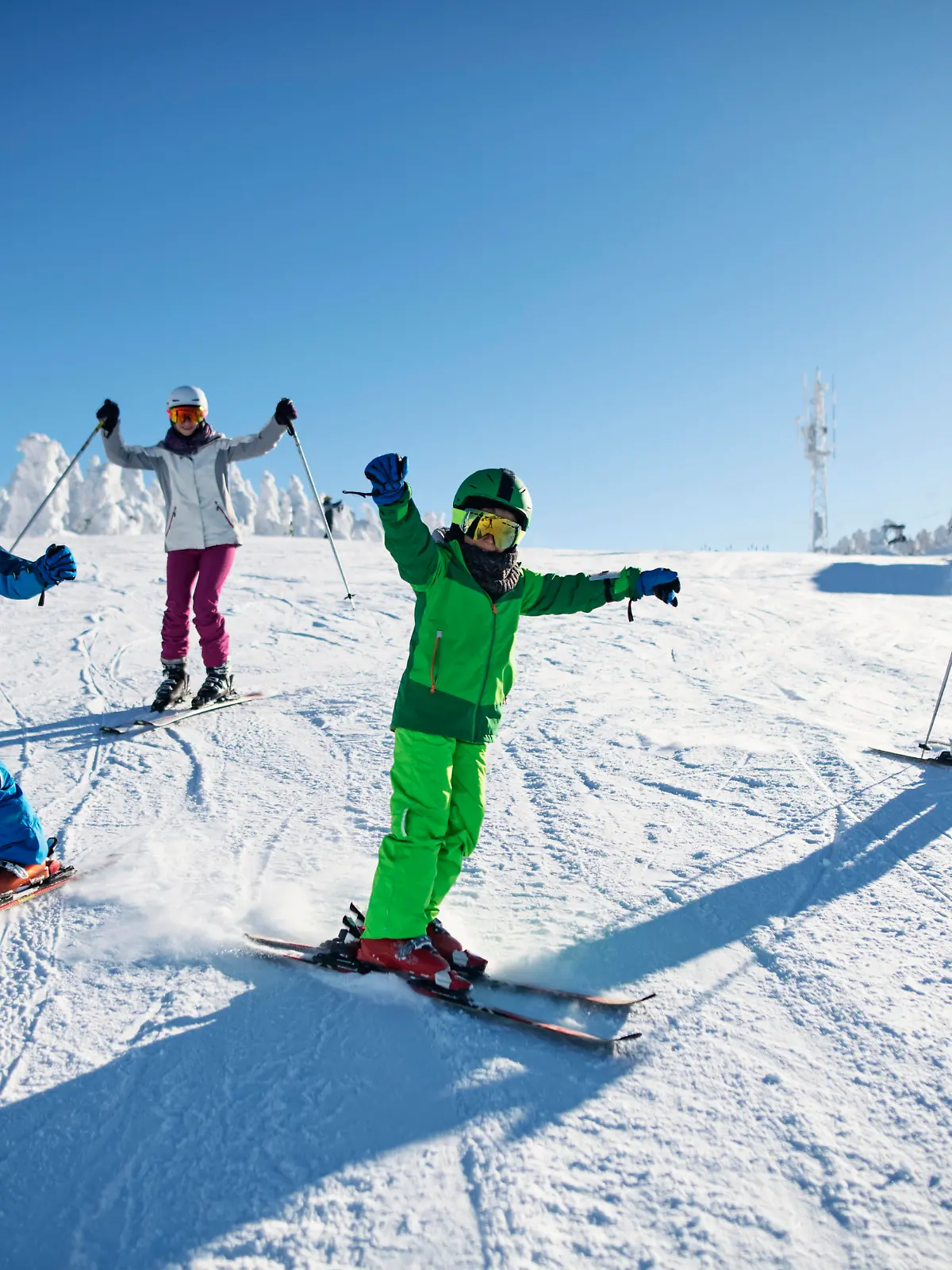 Mother with kids are skiing together down the ski slope. Everybody is laughing happily. 
Sunny winter day.
Nikon D850