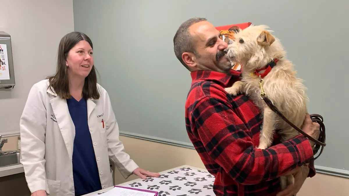 In this image provided by Corinne Martin, Mehrad Houman holds his dog, Mishka, after she was examined by veterinarian Nancy Pillsbury in Harper Woods, Mich., Friday, March 29, 2024. Mishka was discovered in suburban Detroit, eight months after disappearing in San Diego. (Corinne Martin via AP)