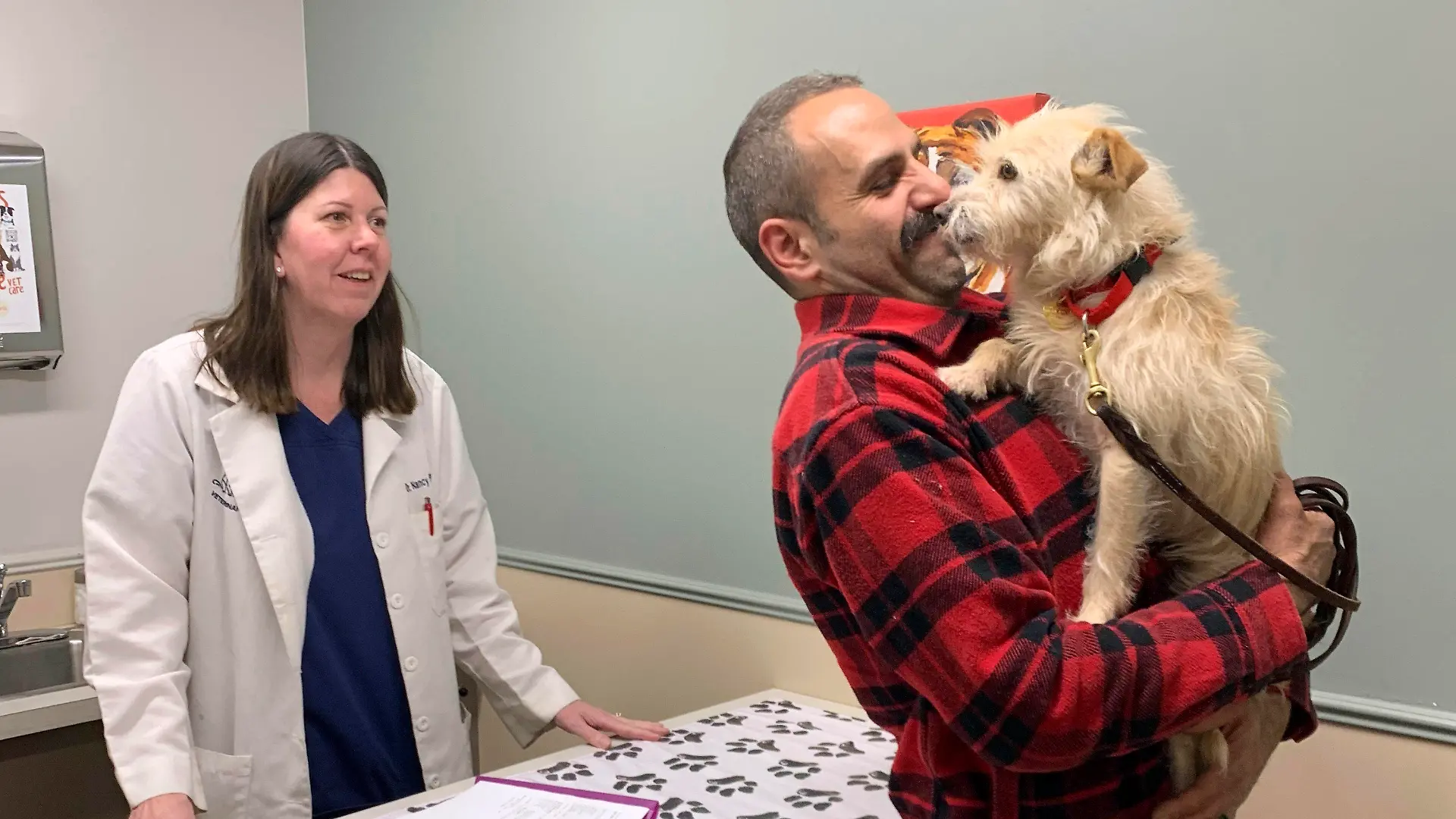 In this image provided by Corinne Martin, Mehrad Houman holds his dog, Mishka, after she was examined by veterinarian Nancy Pillsbury in Harper Woods, Mich., Friday, March 29, 2024. Mishka was discovered in suburban Detroit, eight months after disappearing in San Diego. (Corinne Martin via AP)