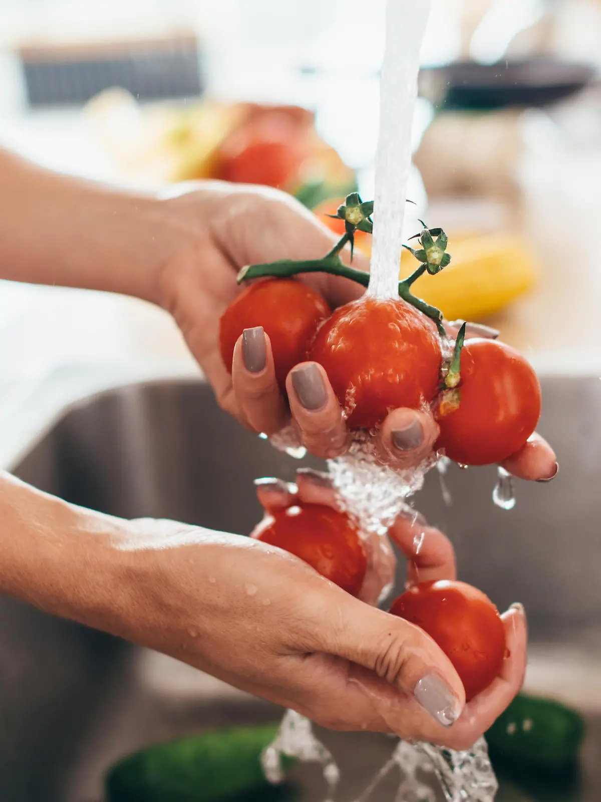 Frau wäscht Tomaten in der Spüle.