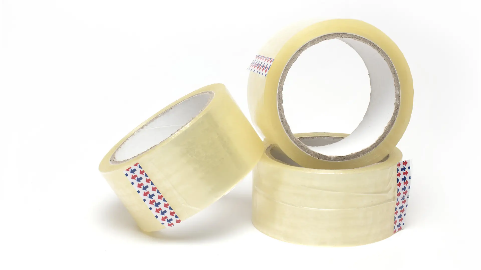 Close up of three rolls of transparent package adhesive tape stacked on top of each other and side by side on white background