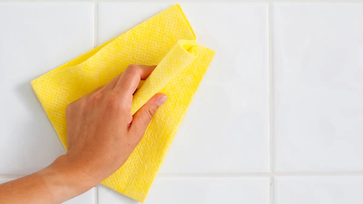 Stock photo of hand cleaning wall with rag