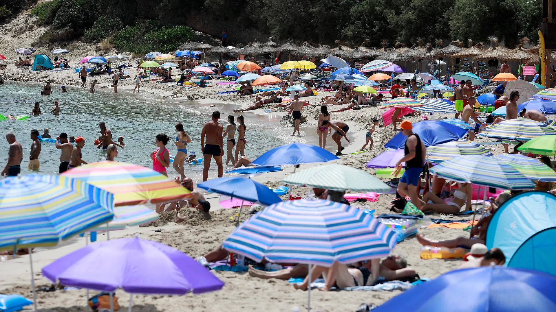 14.08.2022, Spanien, Capdepera: Menschen schwimmen und sonnen sich am Strand Cala Ratjada auf Mallorca. Noch immer herrschen hier hohe Temperaturen und Hitzewarnungen. Foto: Clara Margais/dpa +++ dpa-Bildfunk +++