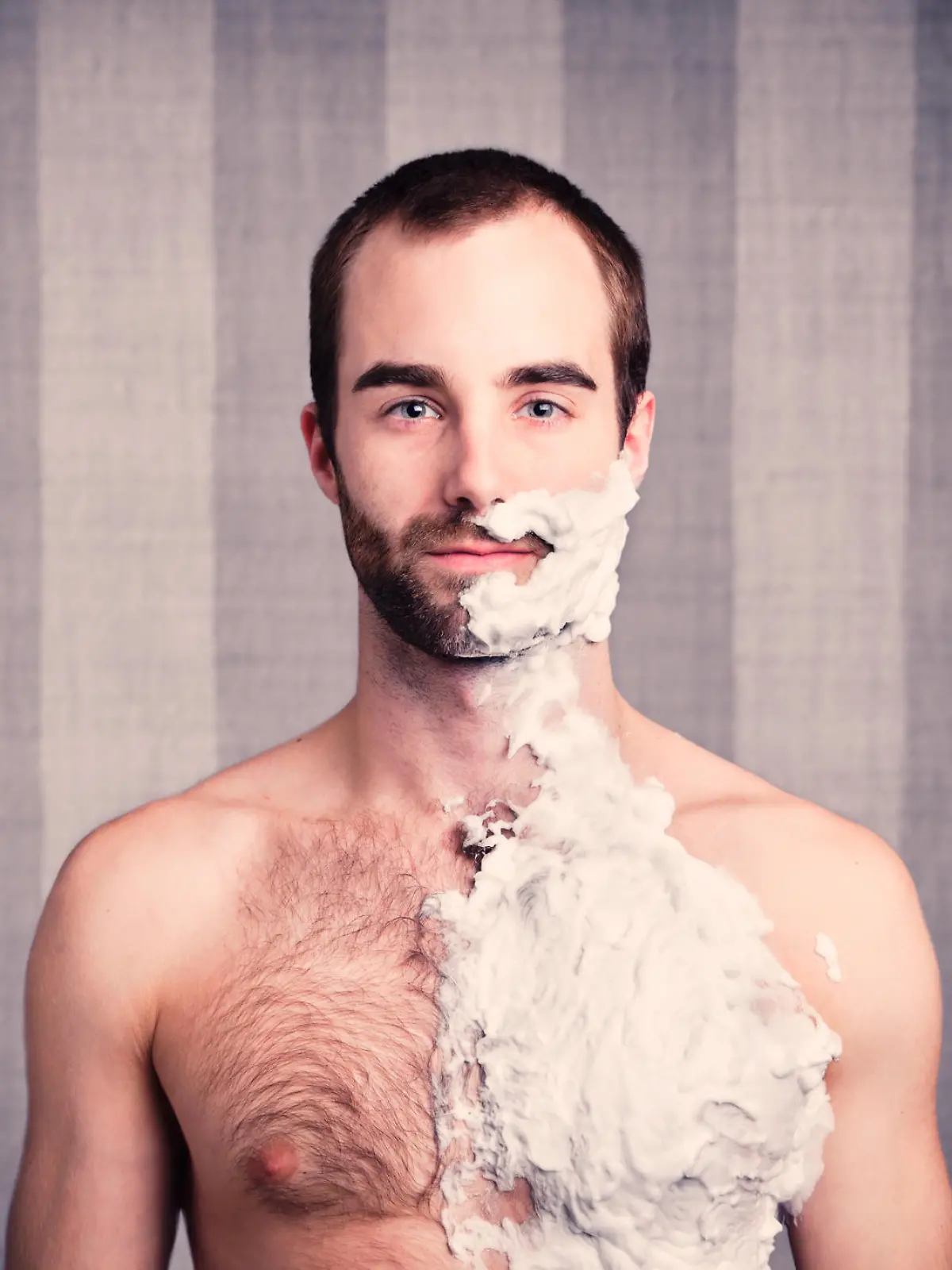 Young hairy man looks straight ahead and breathes in, confident in his decision to shave his body.