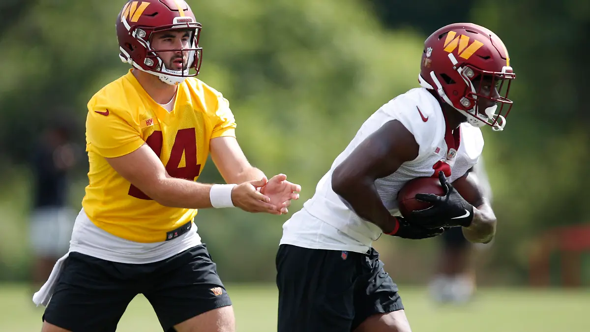 Washington Commanders quarterback Sam Howell, left, hands the ball off to running back Brian Robinson, right, during an NFL football practice at Inova Sports Performance Center in Ashburn, Va., Monday, Aug. 22, 2022. (AP Photo/Luis M. Alvarez)