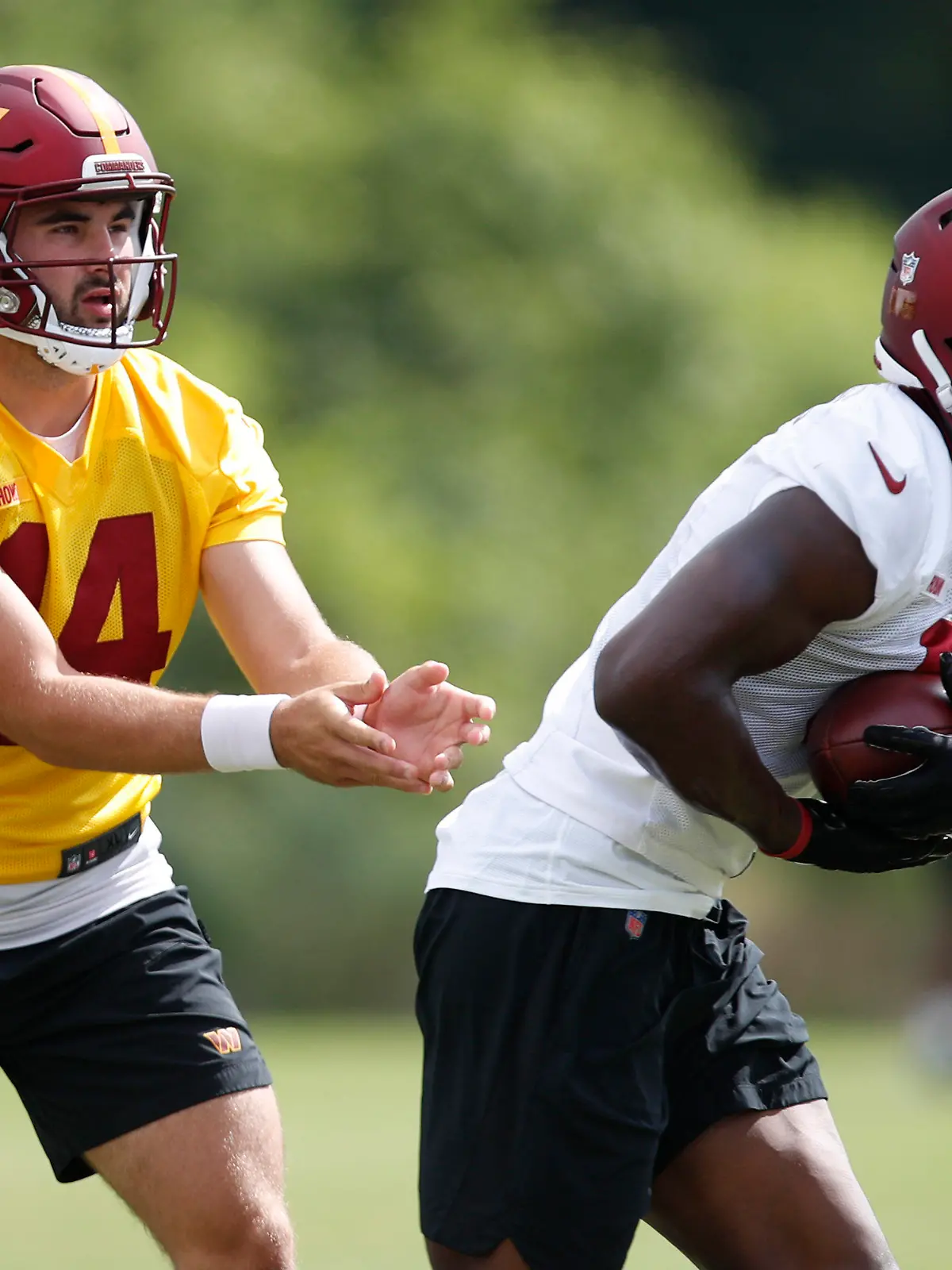 Washington Commanders quarterback Sam Howell, left, hands the ball off to running back Brian Robinson, right, during an NFL football practice at Inova Sports Performance Center in Ashburn, Va., Monday, Aug. 22, 2022. (AP Photo/Luis M. Alvarez)