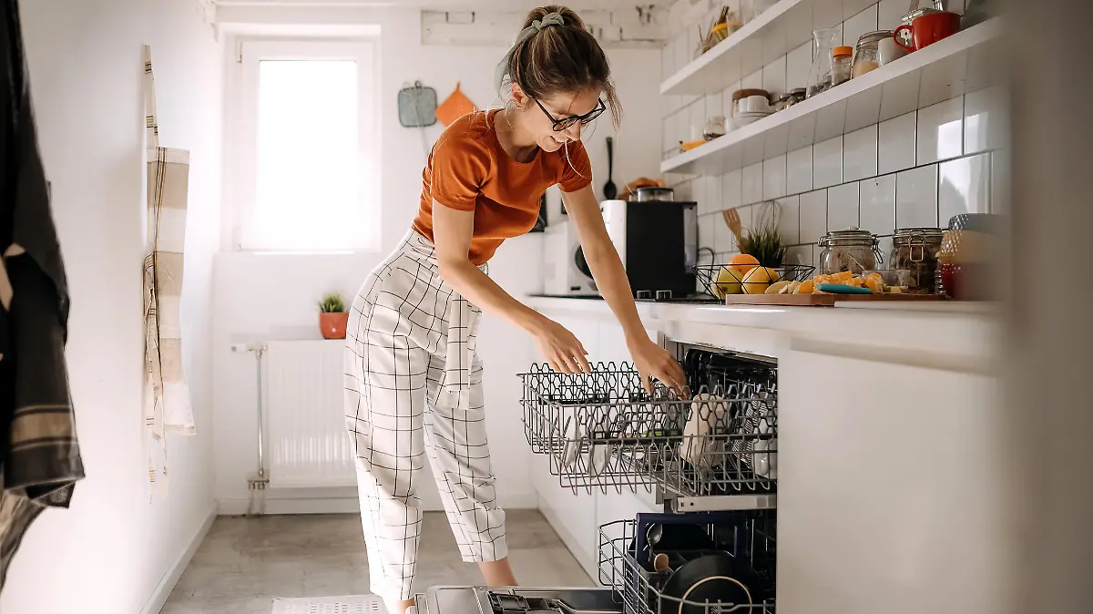 Young woman putting dishes in dishwashing machine