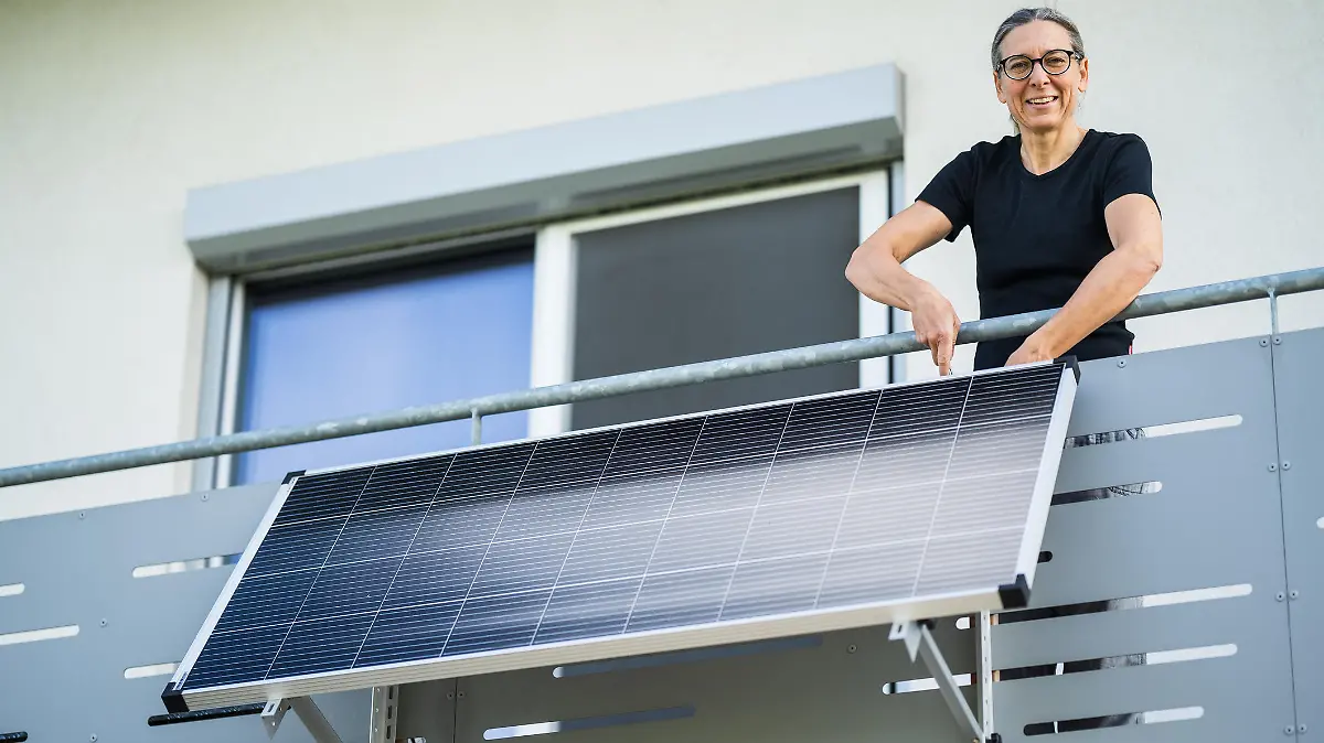 mature adult woman installing adjustable solar panel on balcony of her house smiling at camera