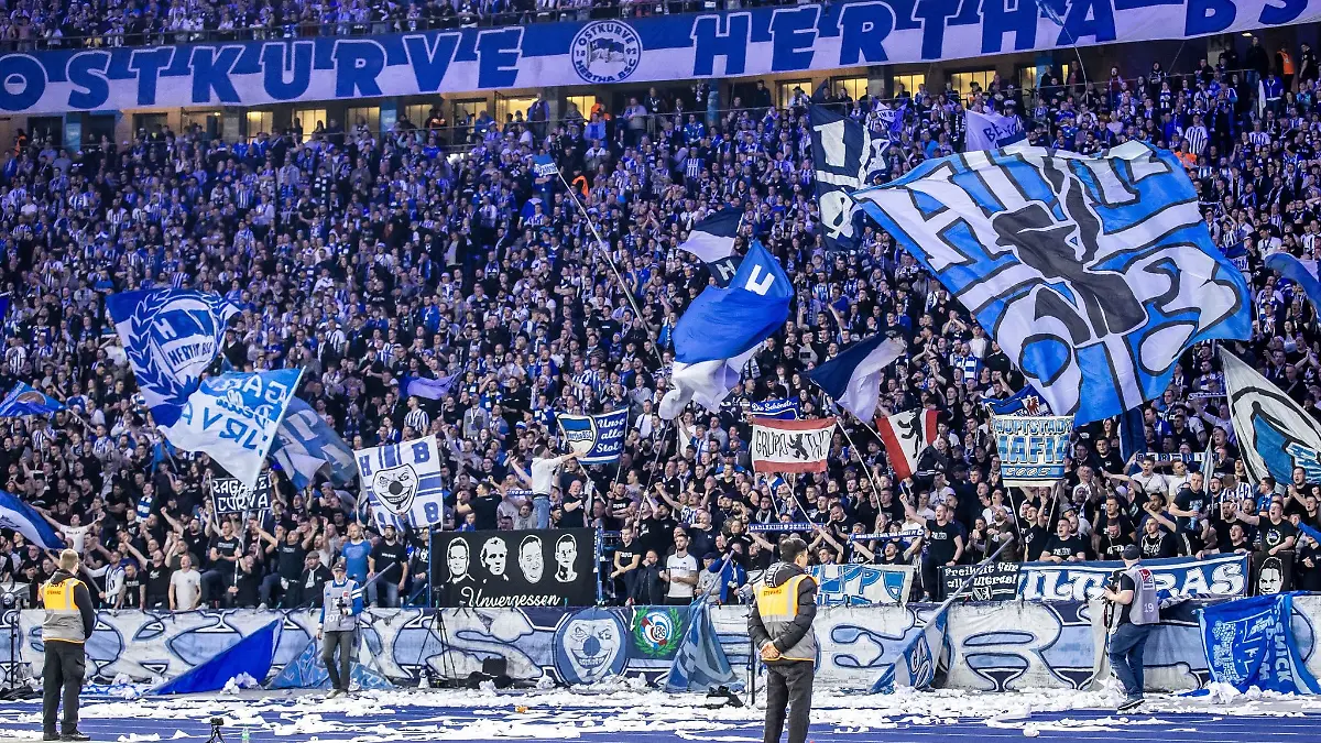 Fans von Hertha BSC feuern ihr Team aus der Ostkurve mit Fahnen an.