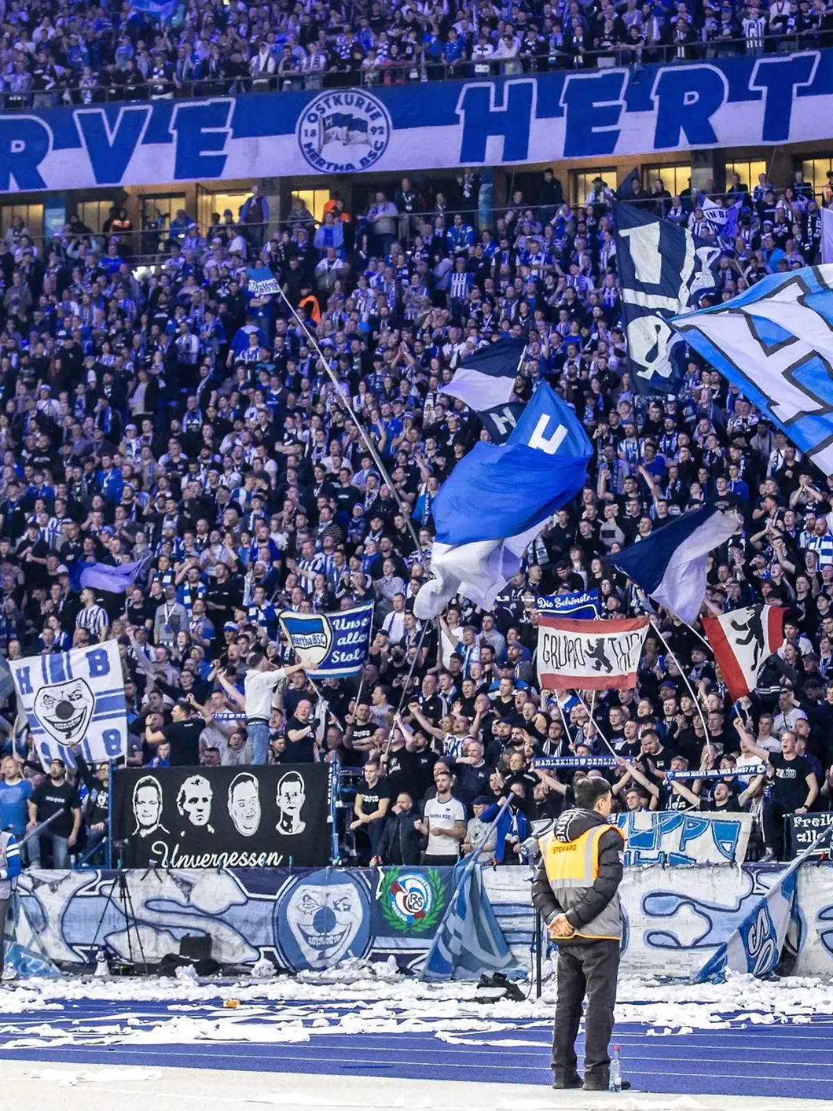 Fans von Hertha BSC feuern ihr Team aus der Ostkurve mit Fahnen an.