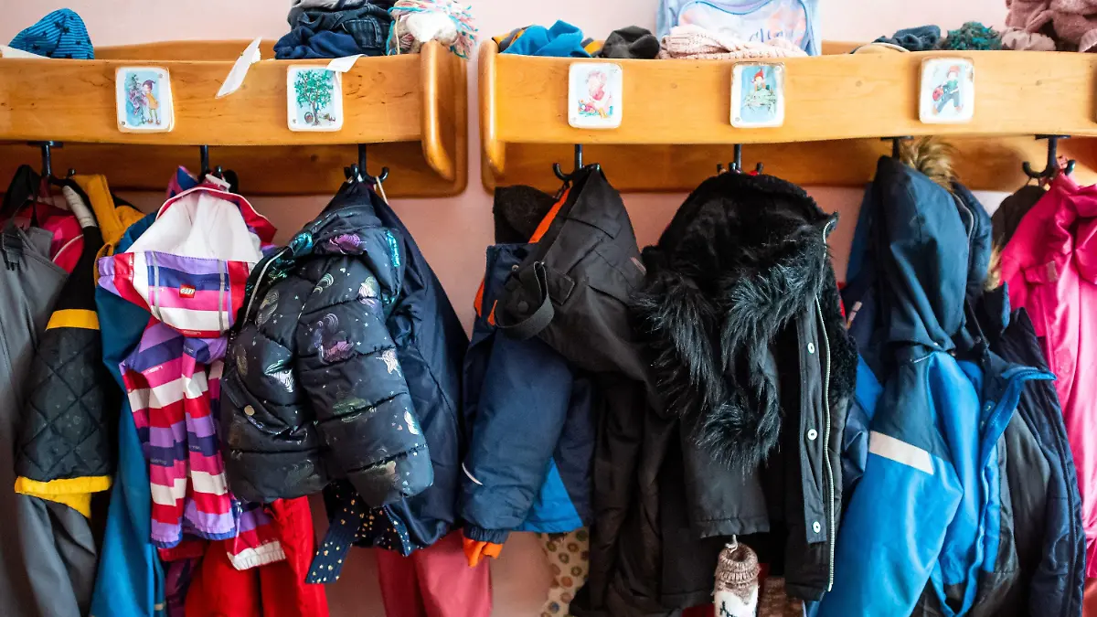08.03.2021, Niedersachsen, Delmenhorst: Kinderjacken und Rucksäcke hängen an der Garderobe in einer Kita. In Regionen, deren Sieben-Tage-Wert an drei aufeinanderfolgenden Tagen unter 100 Neuinfektionen pro 100 000 Einwohner liegt, kehren die Kitas in den eingeschränkten Regelbetrieb zurück. Foto: Sina Schuldt/dpa +++ dpa-Bildfunk +++