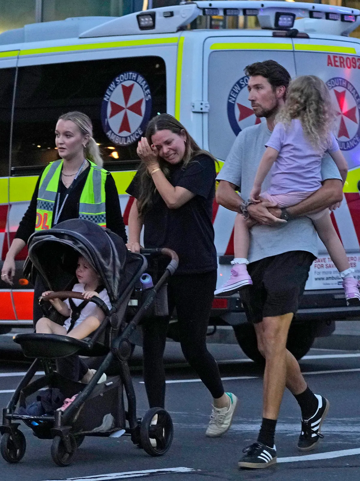 People are led out from the Westfield Shopping Centre where multiple people were stabbed in Sydney, Saturday, April 13, 2024. A man stabbed six people to death at the busy Sydney shopping center Saturday before he was fatally shot, police said. (AP Photo/Rick Rycroft)