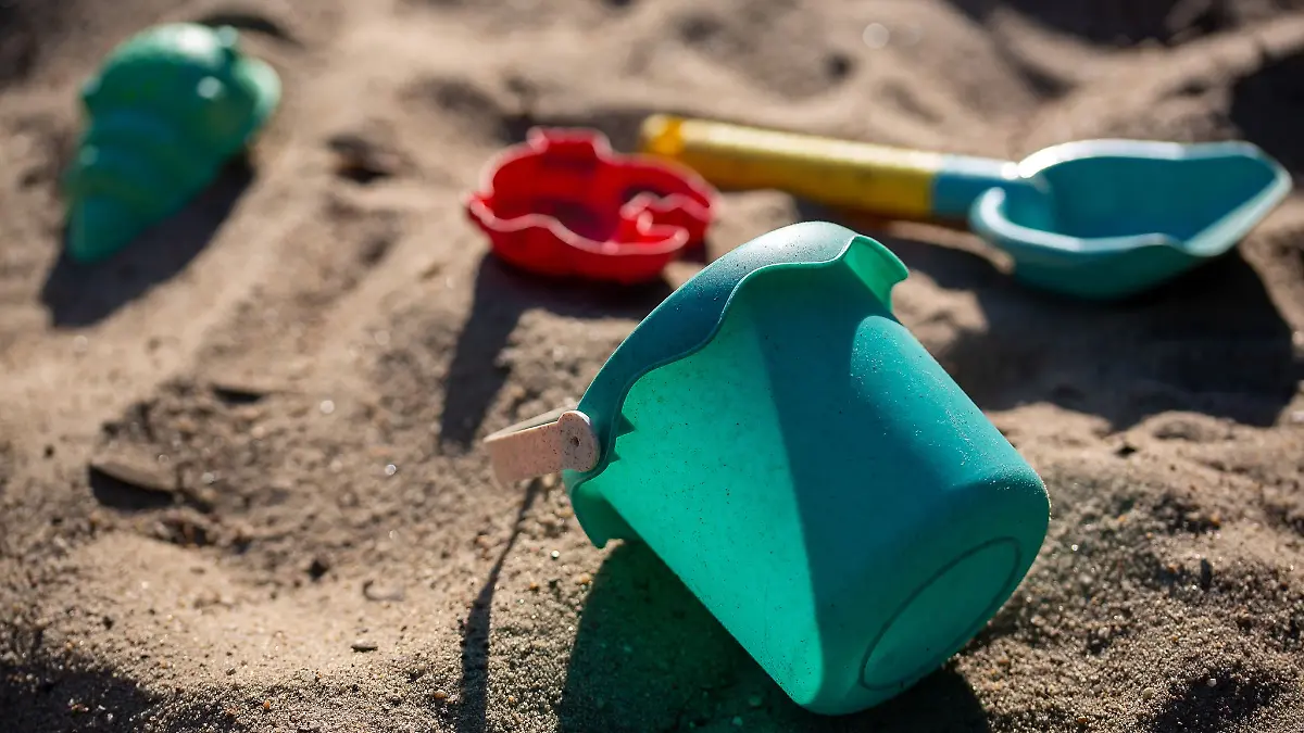 Sandspielzeug liegt auf einem Spielplatz in einem Sandkasten.