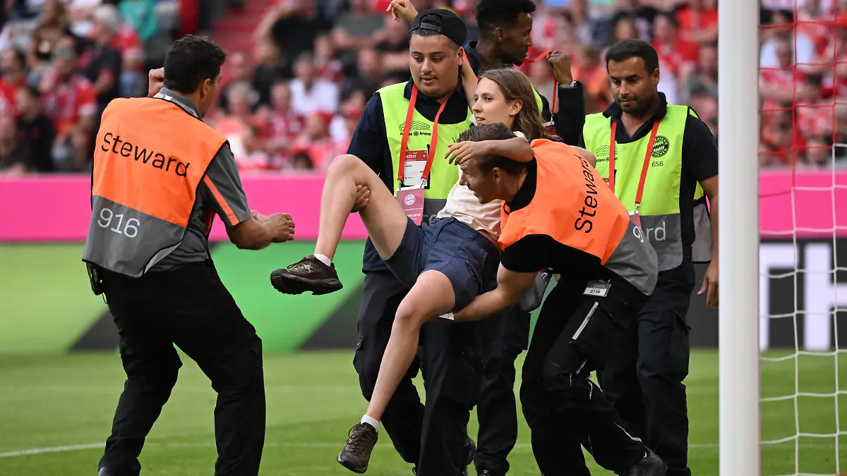 Fußball, Bundesliga, 4. Spieltag, Bayern München - Bor. Mönchengladbach, Allianz Arena: Eine junge Frau, die während des Spiels auf das Spielfeld gerannt war, wird von Ordnern weg getragen. WICHTIGER HINWEIS: Gemäß den Vorgaben der DFL Deutsche Fußball Liga bzw. des DFB Deutscher Fußball-Bund ist es untersagt, in dem Stadion und/oder vom Spiel angefertigte Fotoaufnahmen in Form von Sequenzbildern und/oder videoähnlichen Fotostrecken zu verwerten bzw. verwerten zu lassen.