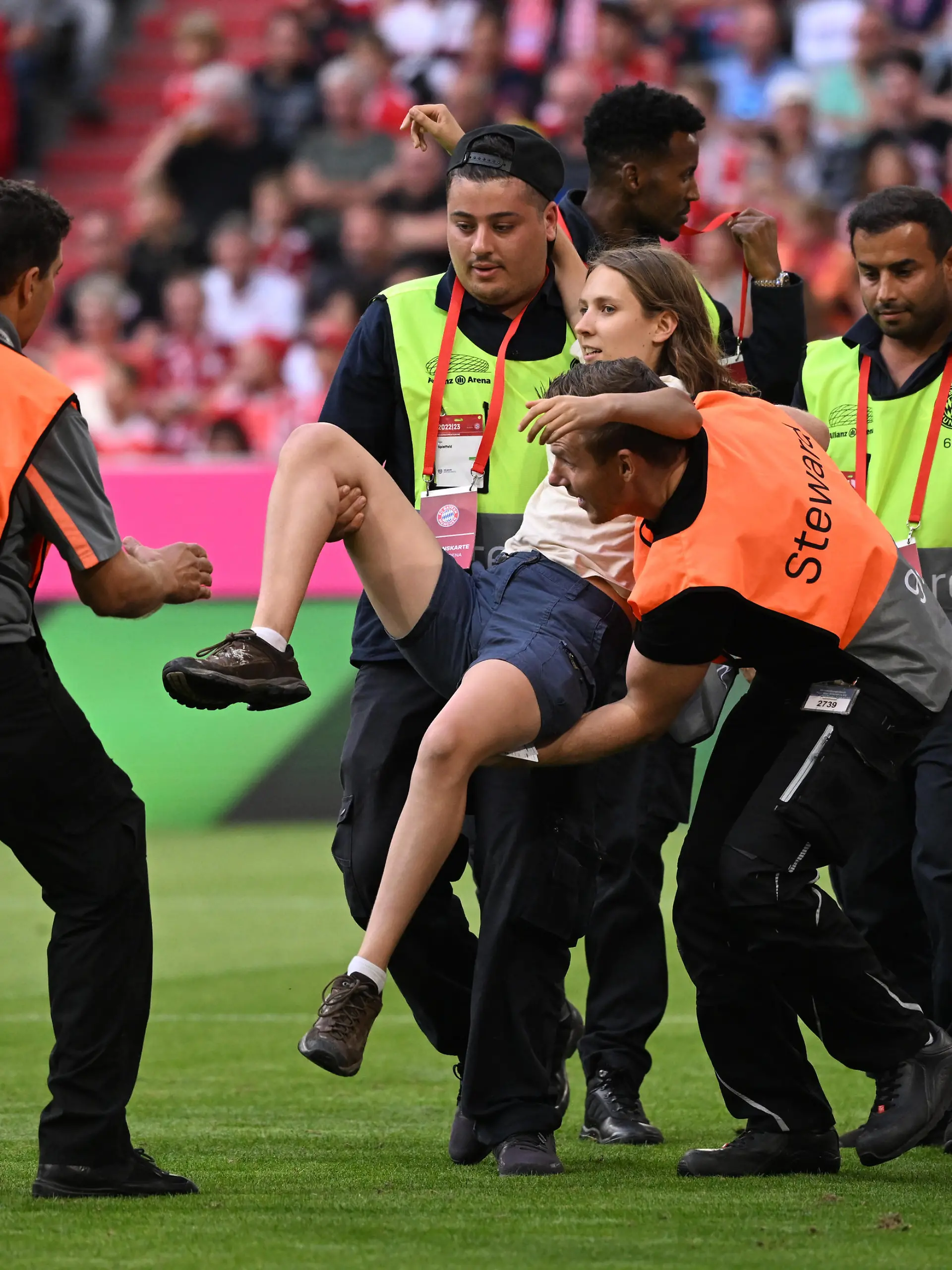 Fußball, Bundesliga, 4. Spieltag, Bayern München - Bor. Mönchengladbach, Allianz Arena: Eine junge Frau, die während des Spiels auf das Spielfeld gerannt war, wird von Ordnern weg getragen. WICHTIGER HINWEIS: Gemäß den Vorgaben der DFL Deutsche Fußball Liga bzw. des DFB Deutscher Fußball-Bund ist es untersagt, in dem Stadion und/oder vom Spiel angefertigte Fotoaufnahmen in Form von Sequenzbildern und/oder videoähnlichen Fotostrecken zu verwerten bzw. verwerten zu lassen.