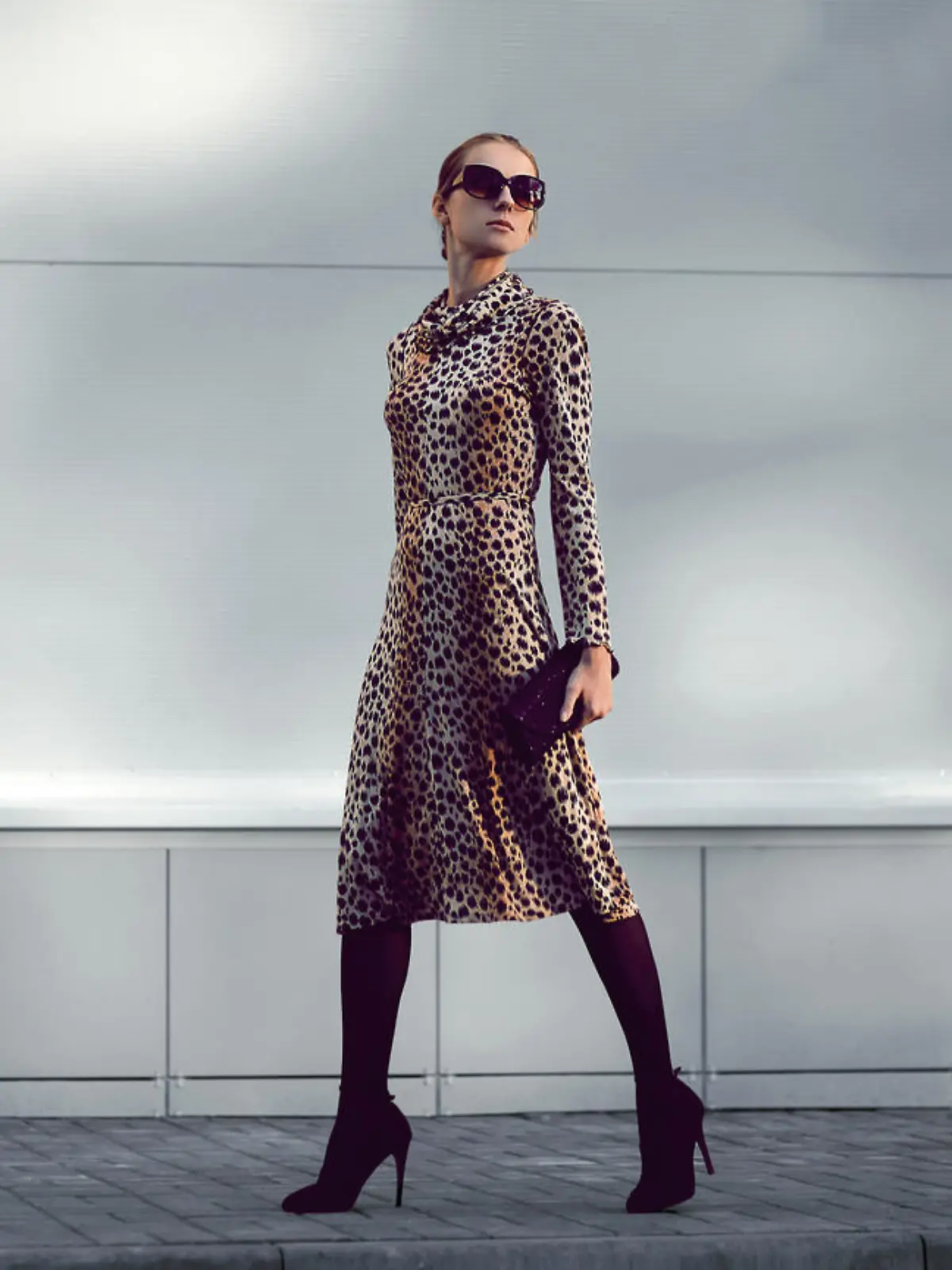Elegant woman model in leopard dress walking in evening city, street fashion concept