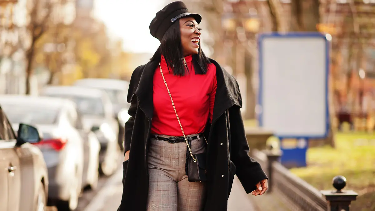African american fashion girl in coat and newsboy cap posed at street.