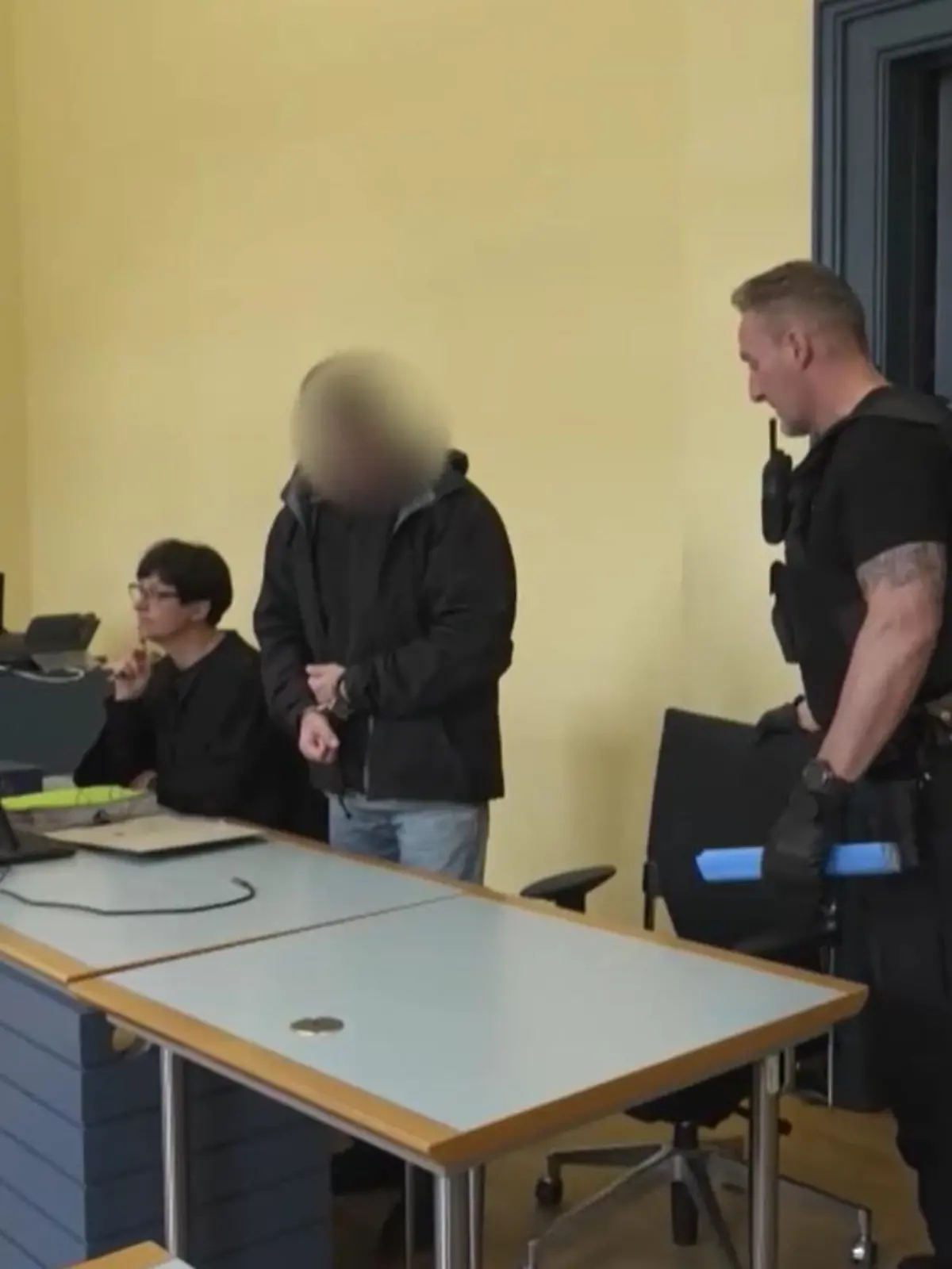Ein Mann wird von Justizbeamten in den Gerichtssaal geführt.