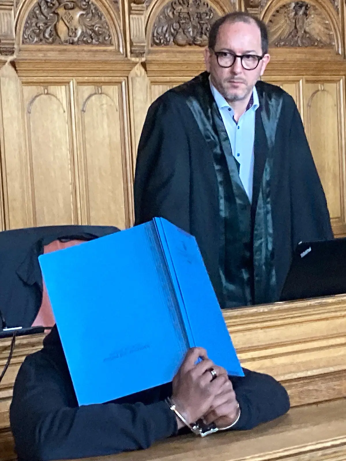 17.04.2024, Bremen: Der Angeklagte sitzt in einem Saal des Landgerichts, hinter ihm steht sein  Verteidiger Alexander Gellinger. Die Staatsanwaltschaft wirft ihm vor, seine Schwester im Dezember vergangenen Jahres mit einem Küchenmesser in ihrer Wohnung getötet zu haben. Nach Auffassung der Anklagebehörde war er mit ihrem Lebenswandel nicht einverstanden. Er sah demnach die Ehre seiner Familie geschädigt und wollte diese mit ihrem Tod wiederherstellen. Foto: Mirjam Uhrich/dpa +++ dpa-Bildfunk +++