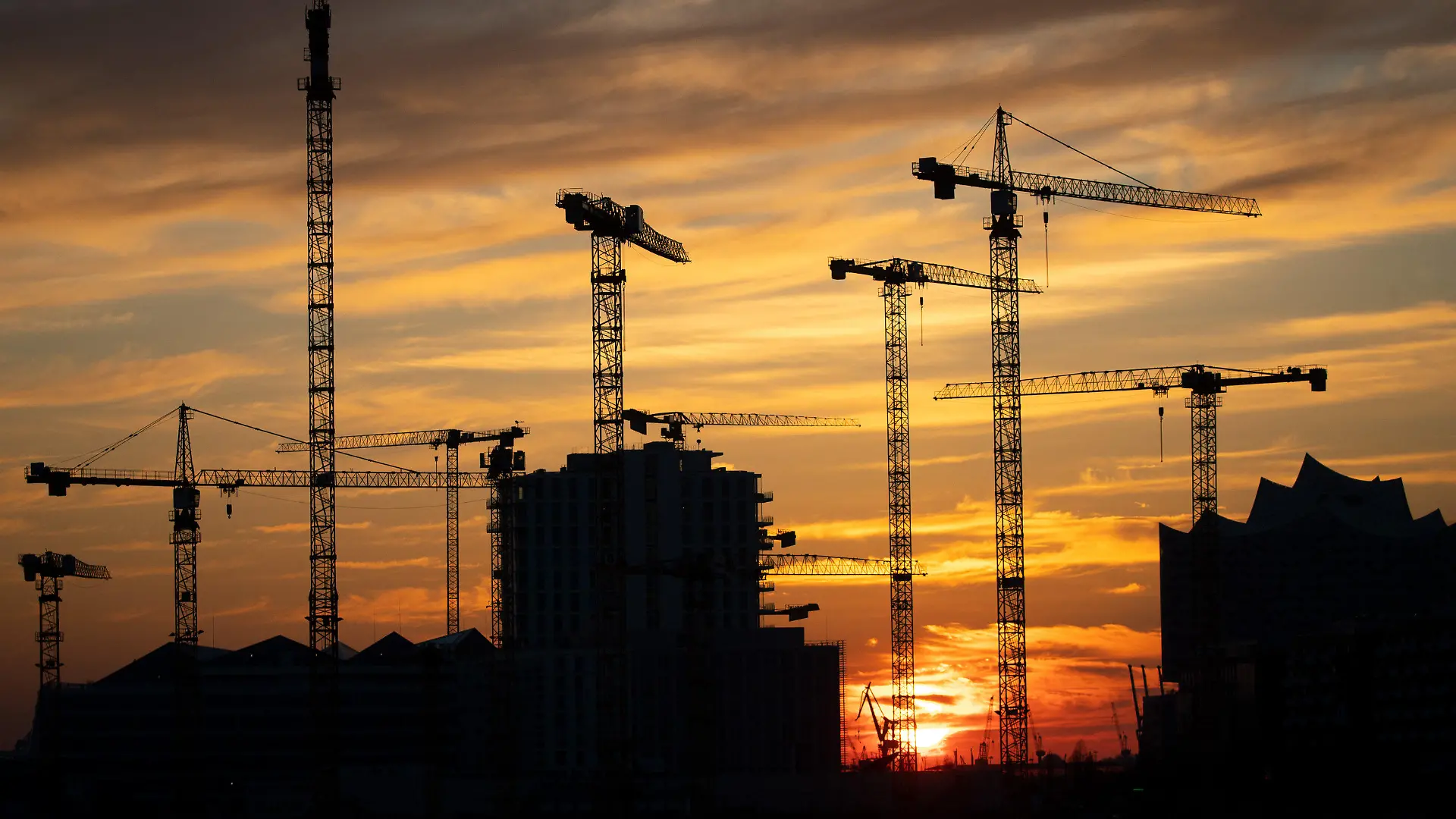 ARCHIV - 25.03.2020, Hamburg: Die Kräne verschiedener Baustellen in der Hafencity zeichnen sich im Sonnenuntergang ab. Wie sich die Finanzen von Bund, Ländern, Gemeinden und Sozialversicherung im ersten Halbjahr 2022 entwickelt haben, gibt das Statistische Bundesamt am Donnerstag bekannt. (zu dpa «Statistiker geben Daten zu Staatshaushalt und Konjunktur bekannt») Foto: Christian Charisius/dpa +++ dpa-Bildfunk +++