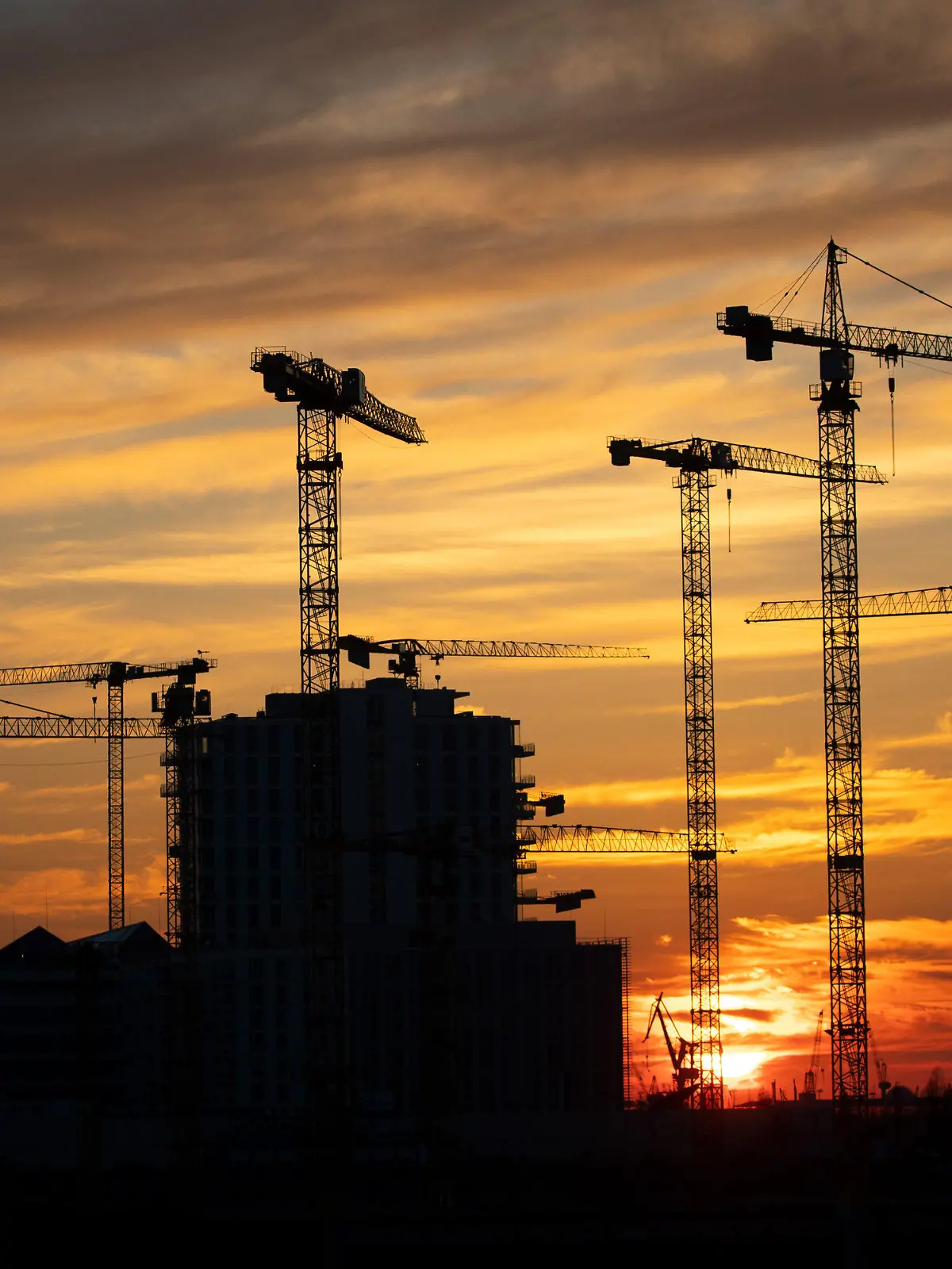 ARCHIV - 25.03.2020, Hamburg: Die Kräne verschiedener Baustellen in der Hafencity zeichnen sich im Sonnenuntergang ab. Wie sich die Finanzen von Bund, Ländern, Gemeinden und Sozialversicherung im ersten Halbjahr 2022 entwickelt haben, gibt das Statistische Bundesamt am Donnerstag bekannt. (zu dpa «Statistiker geben Daten zu Staatshaushalt und Konjunktur bekannt») Foto: Christian Charisius/dpa +++ dpa-Bildfunk +++