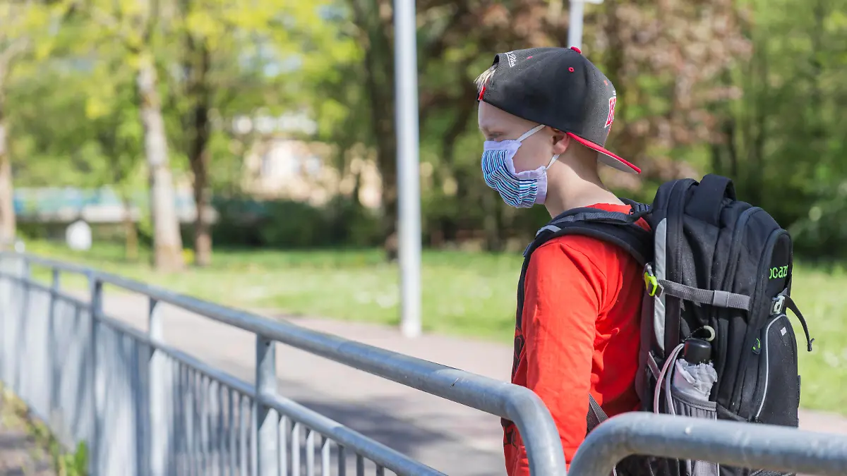 06.05.2020, Corona-Maßnahmen - Maskenpflicht und Schule Ein Junge mit einer Mund-Nasen-Behelfs-Maske und Schulranzen steht an einer Bushaltestelle. Bad Brückenau Bayern Deutschland *** 06 05 2020, Corona measures compulsory mask and school A boy with a mouth nose makeshift mask and school bag is standing at a bus stop Bad Brückenau Bavaria Germany